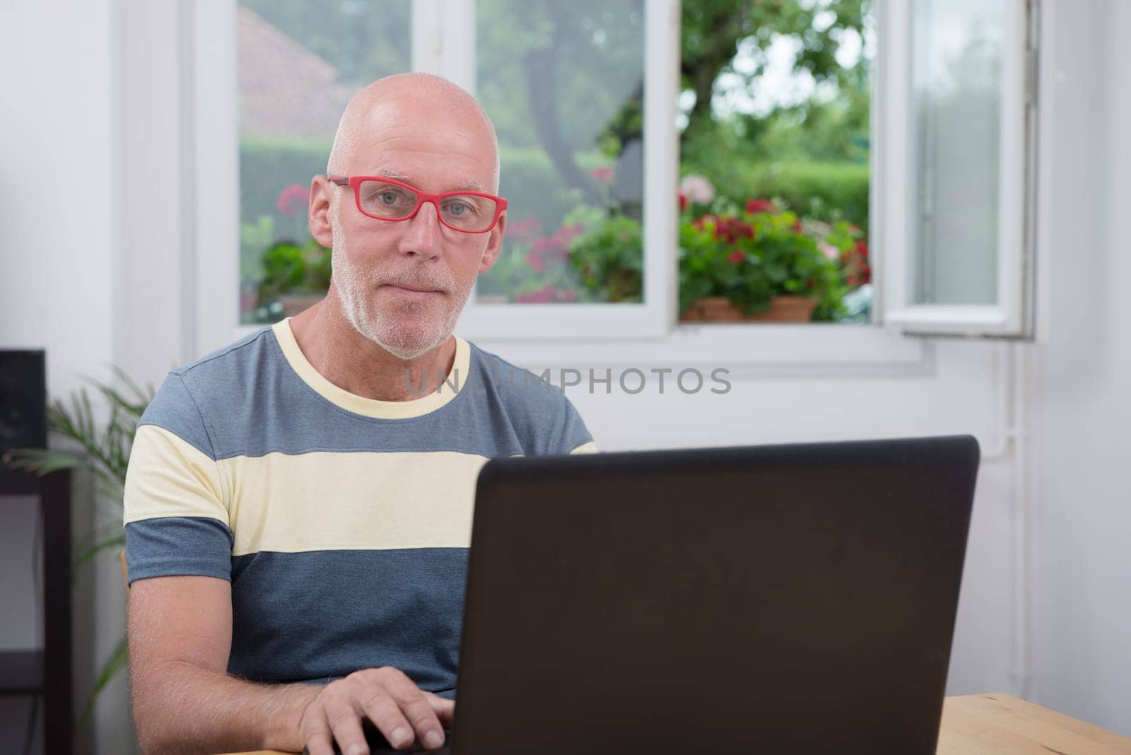 a mature man with laptop in his home