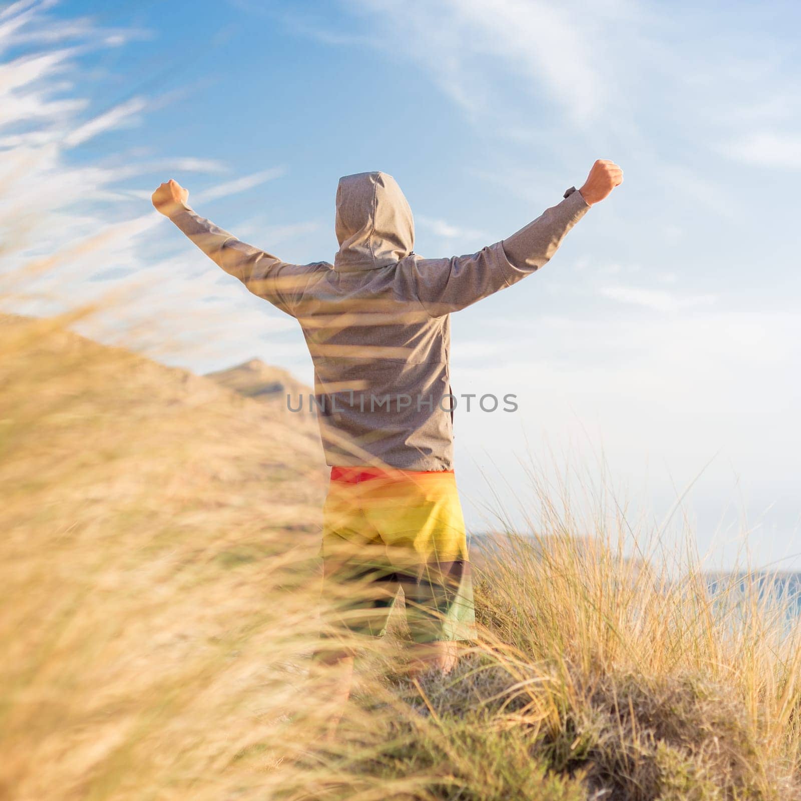 Successful sporty active man, arms rised, enjoying beauty of nature, freedom and life at beautiful landscape at Balos beach, Greece. Active lifestyle outdoors. Made it.