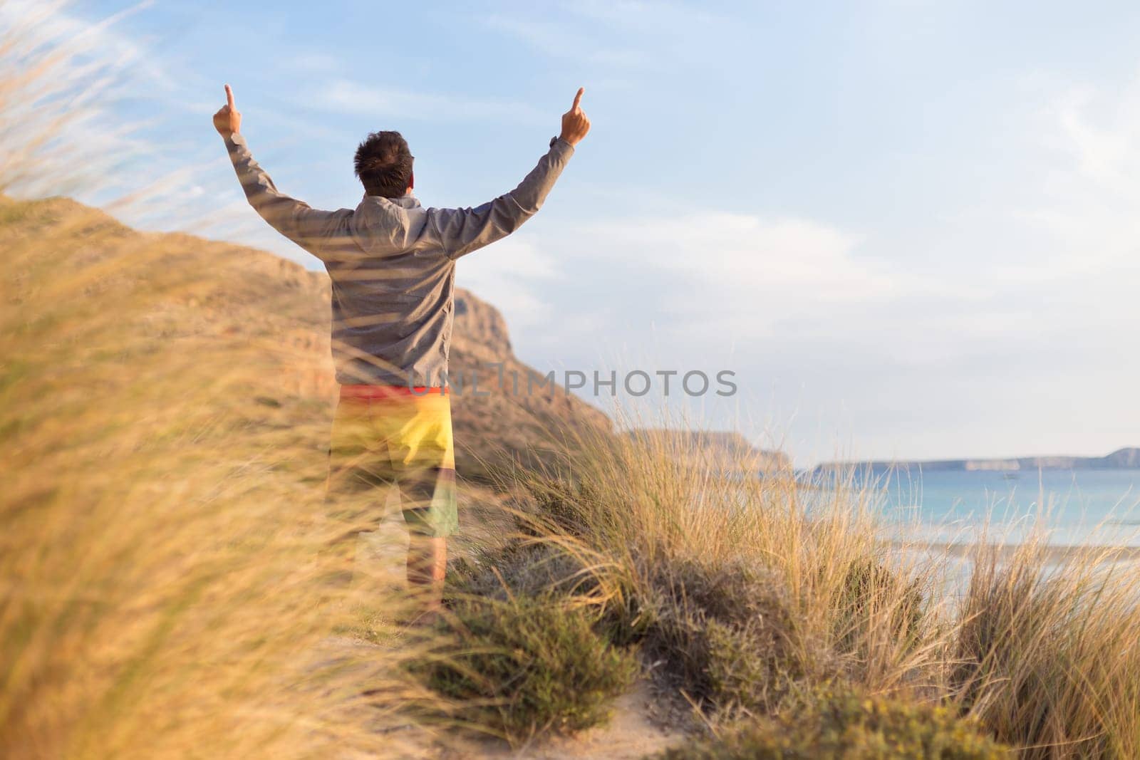 Sporty active man, arms rised, enjoying beauty of nature, freedom and life at beautiful landscape. Active lifestyle outdoors. Made it.