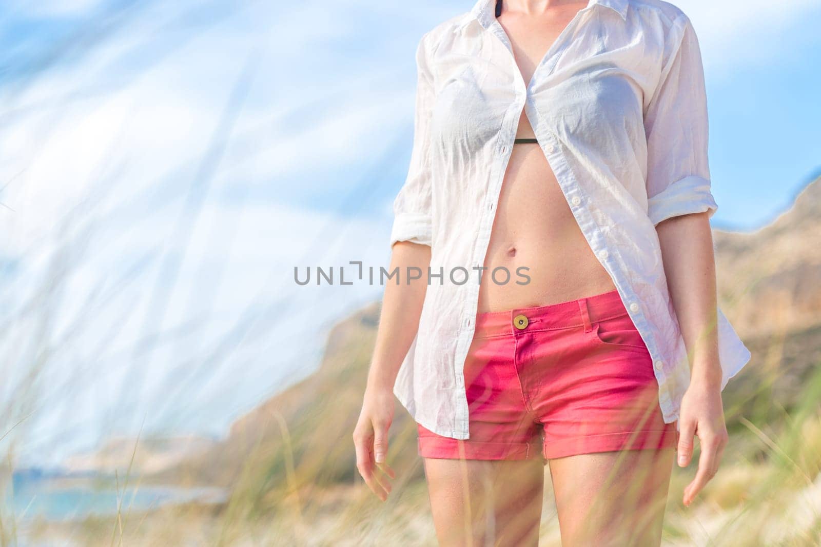 Relaxed woman in unpinned white shirt enjoying beautiful nature at serene landscape at Balos beach, Greece. Concept of vacations, freedom, happiness, joy and well being.