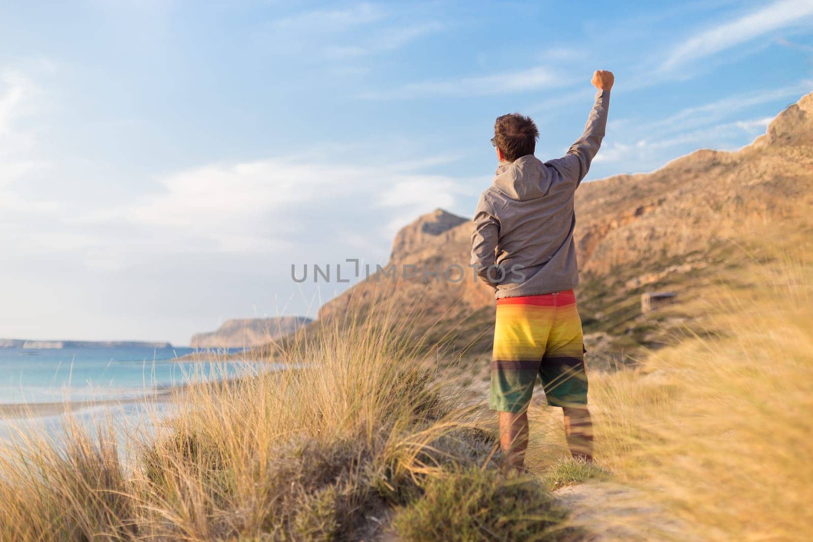 Sporty active man, arm rised, enjoying beauty of nature, freedom and life at beautiful landscape. Active lifestyle outdoors. Made it.