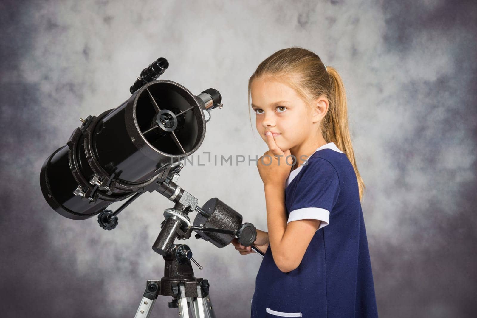Seven-year girl looks at the sky while standing at the telescope