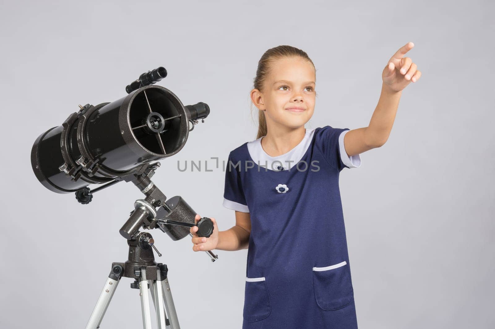The young astronomer shows the starry sky while standing at the telescope