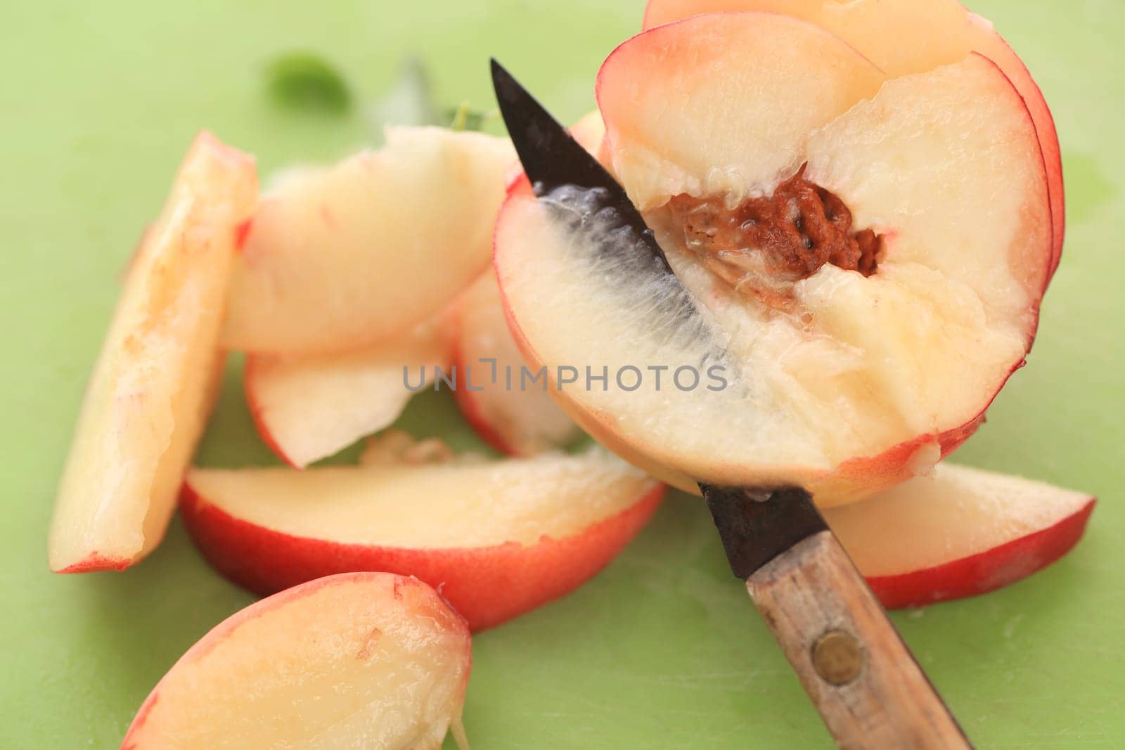 An old paring knife is used to cut an almost transparent slice of fresh fruit.