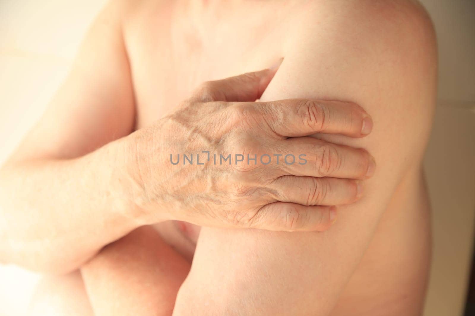 An older man with his hand on an aching arm muscle.