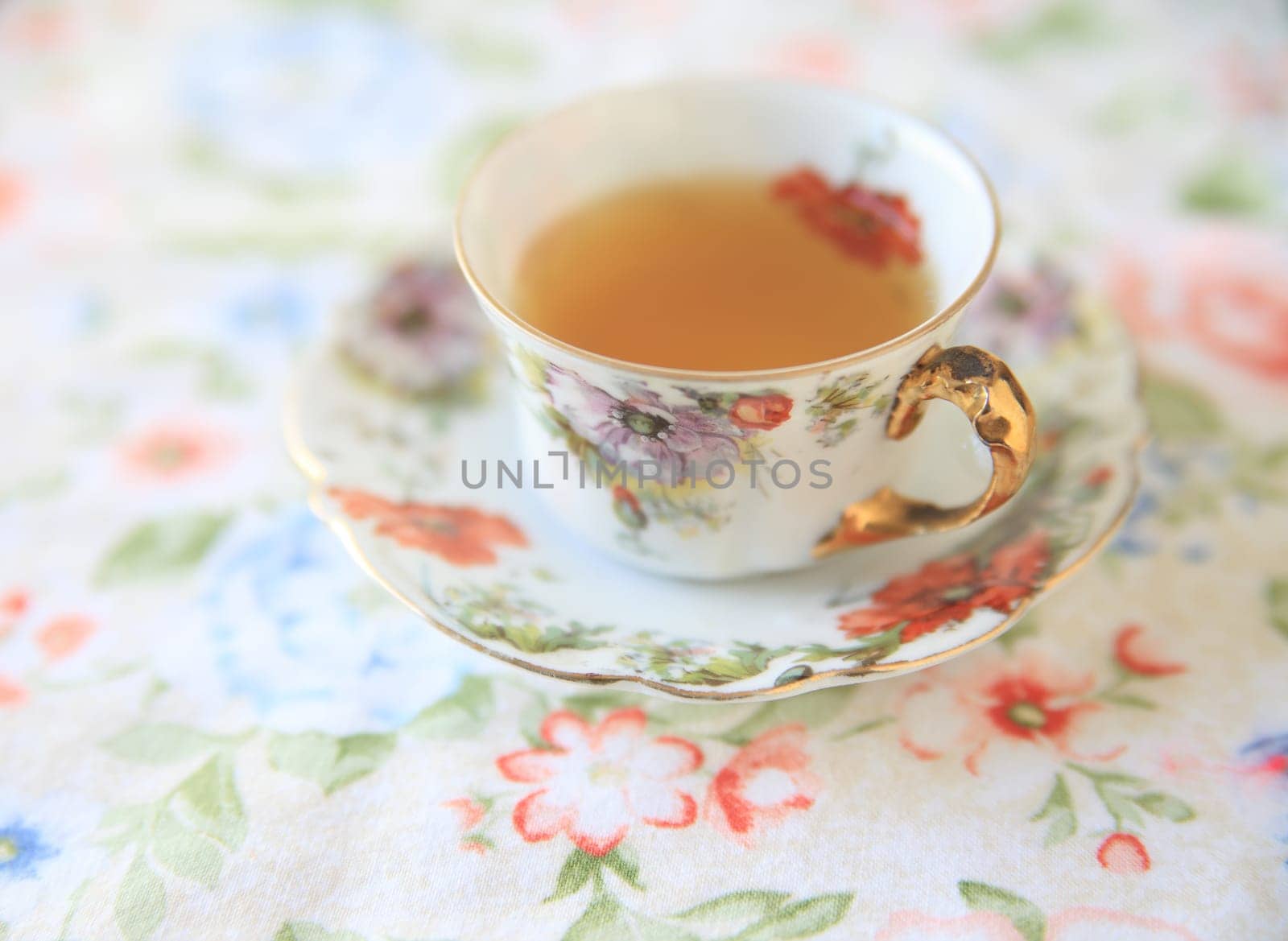 Floral cup with tea on a flowery cloth