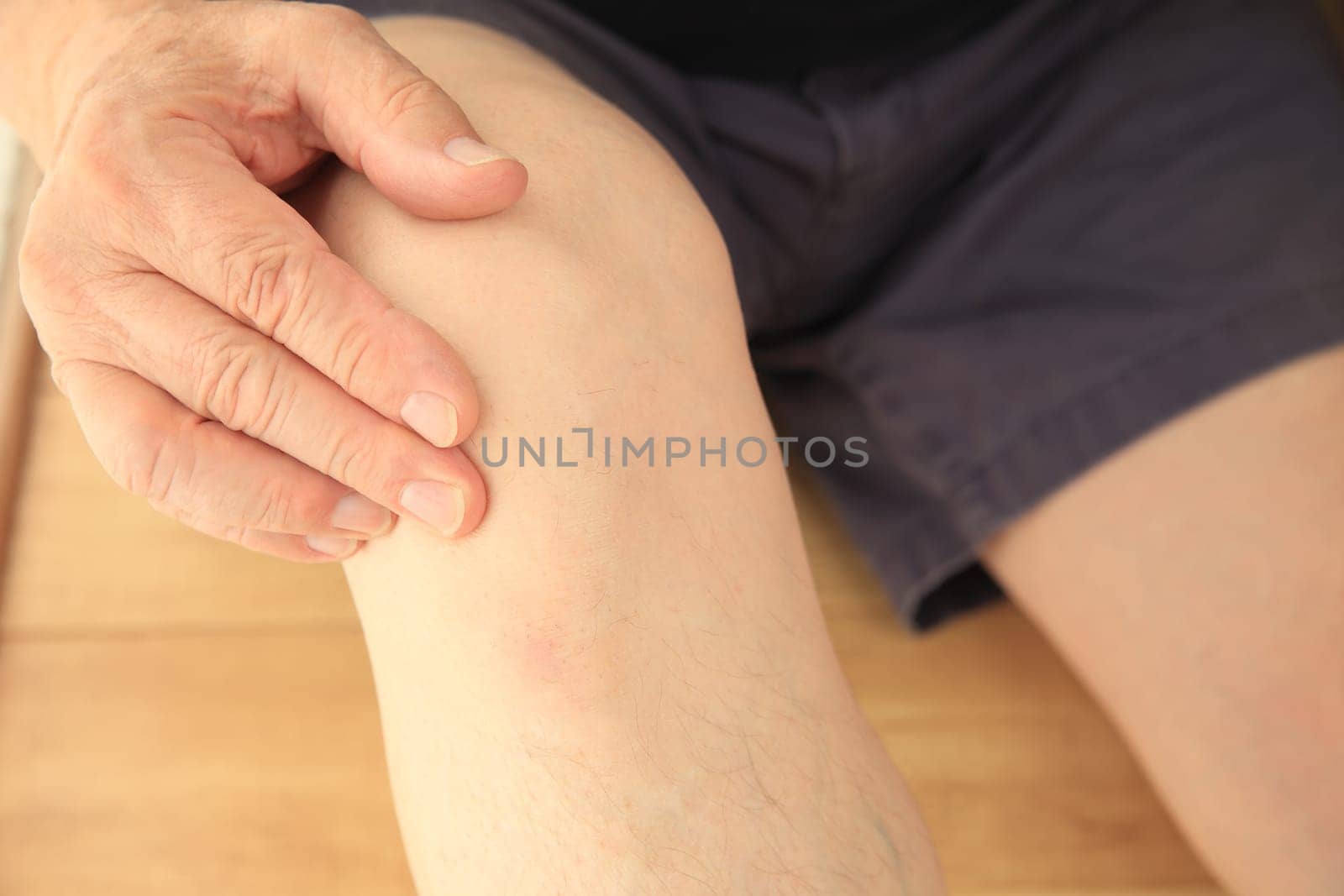 Older man puts a hand on his sore knee joint.