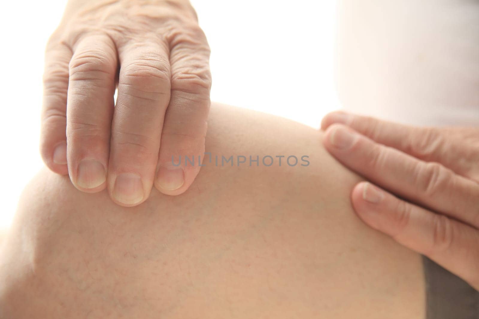 Senior man cautiously presses on his painful knee.