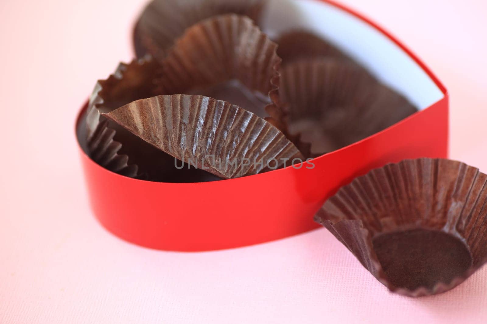 Red heart box  on pink background with only paper candy wrappers left