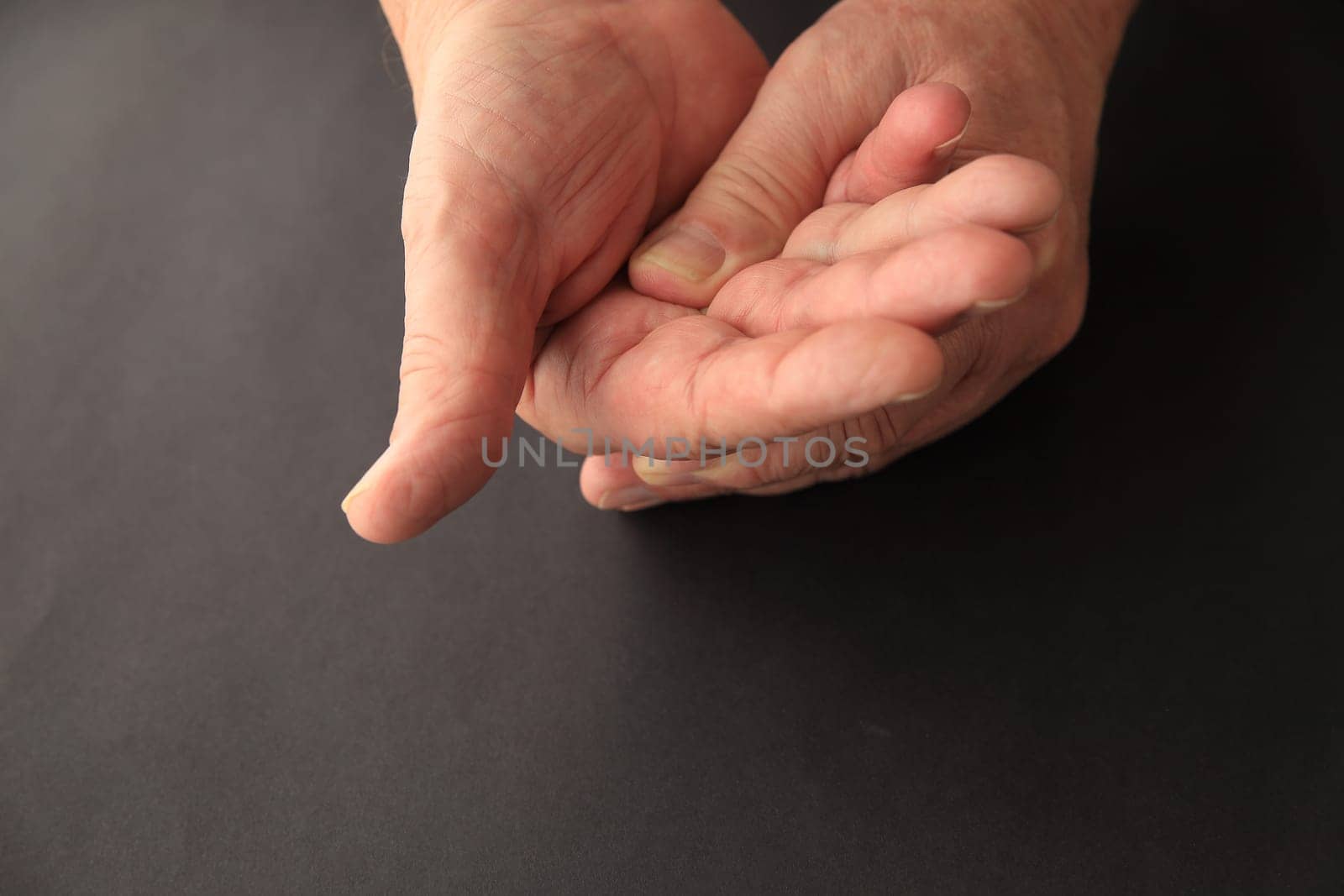 A senior man applies light pressure to the palm of his hand.