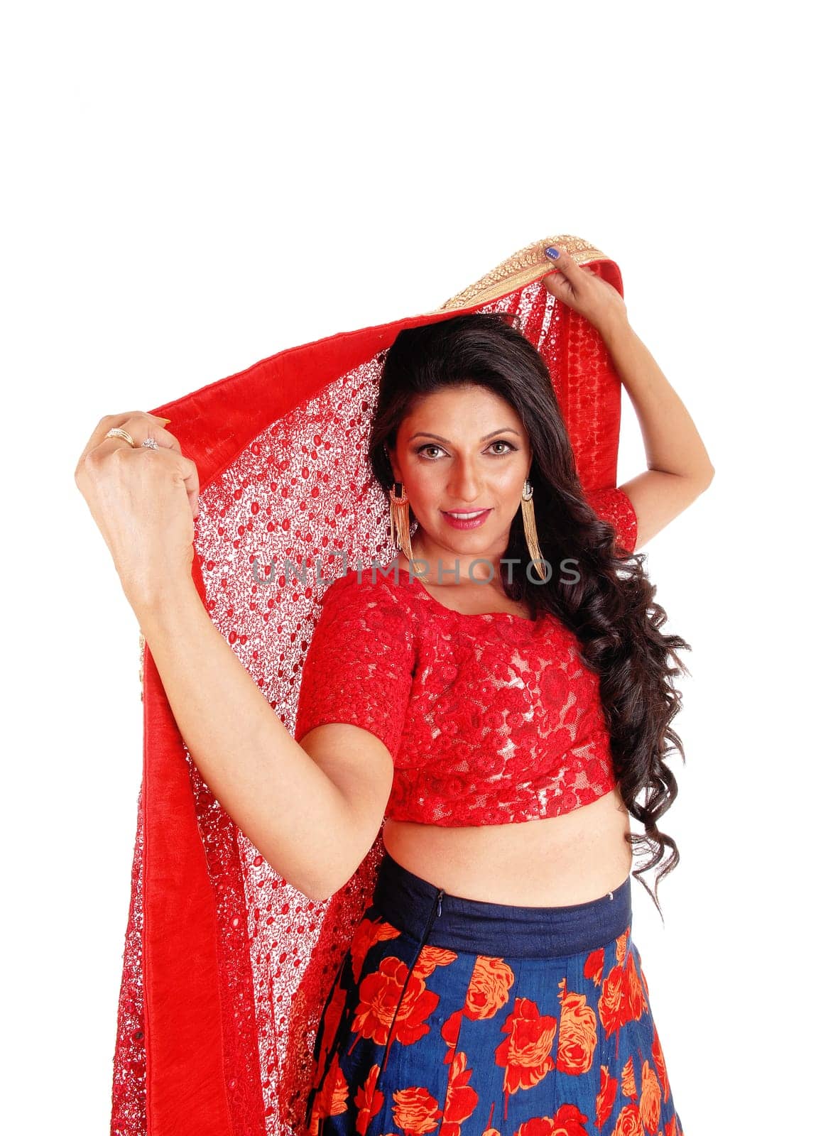 A very pretty woman in a red top and blue skirt holding a red scarf over.her head, isolated for white background..