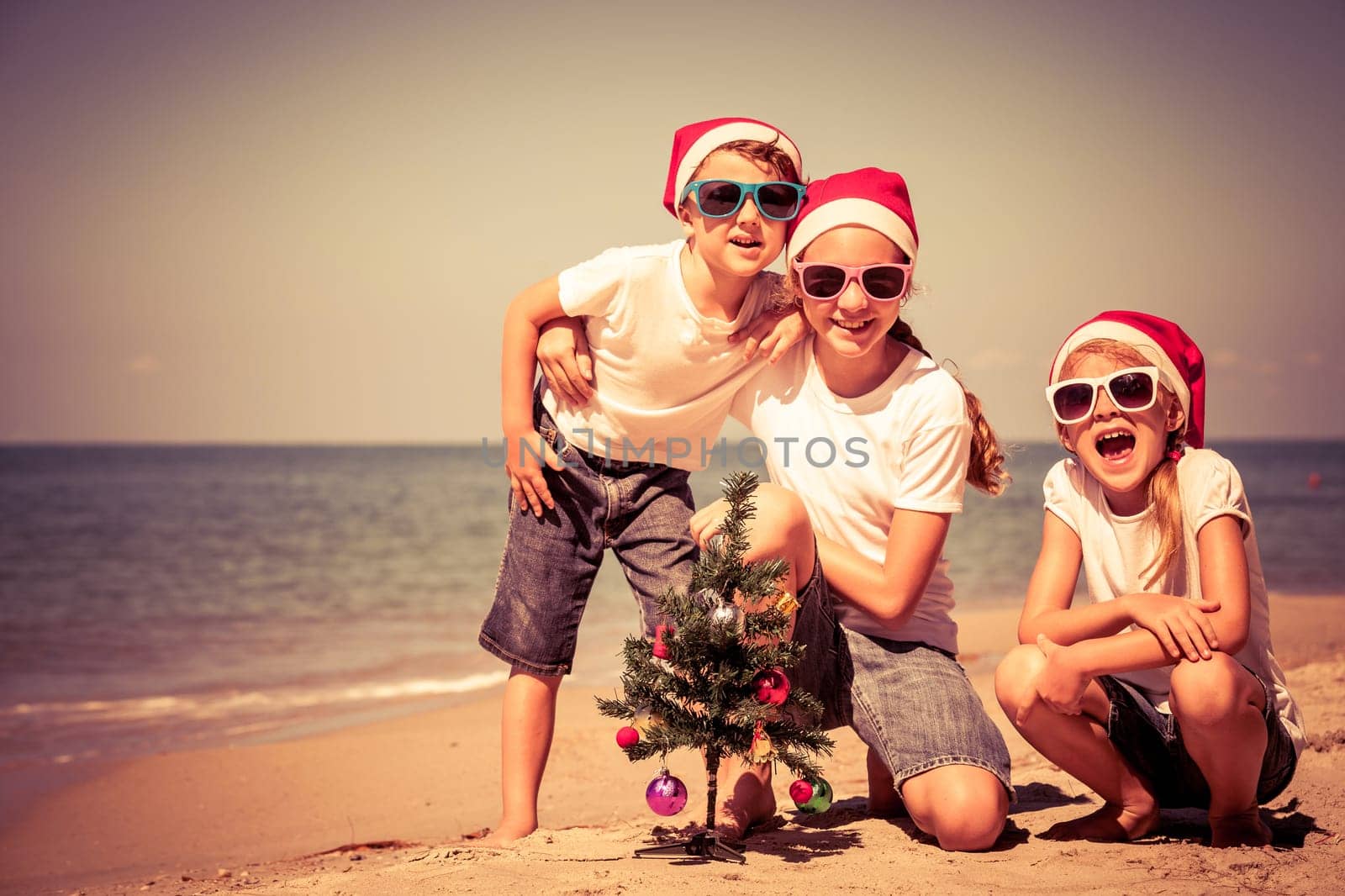 Three happy children  playing on the beach at the day time. Concept of Happy New Year.