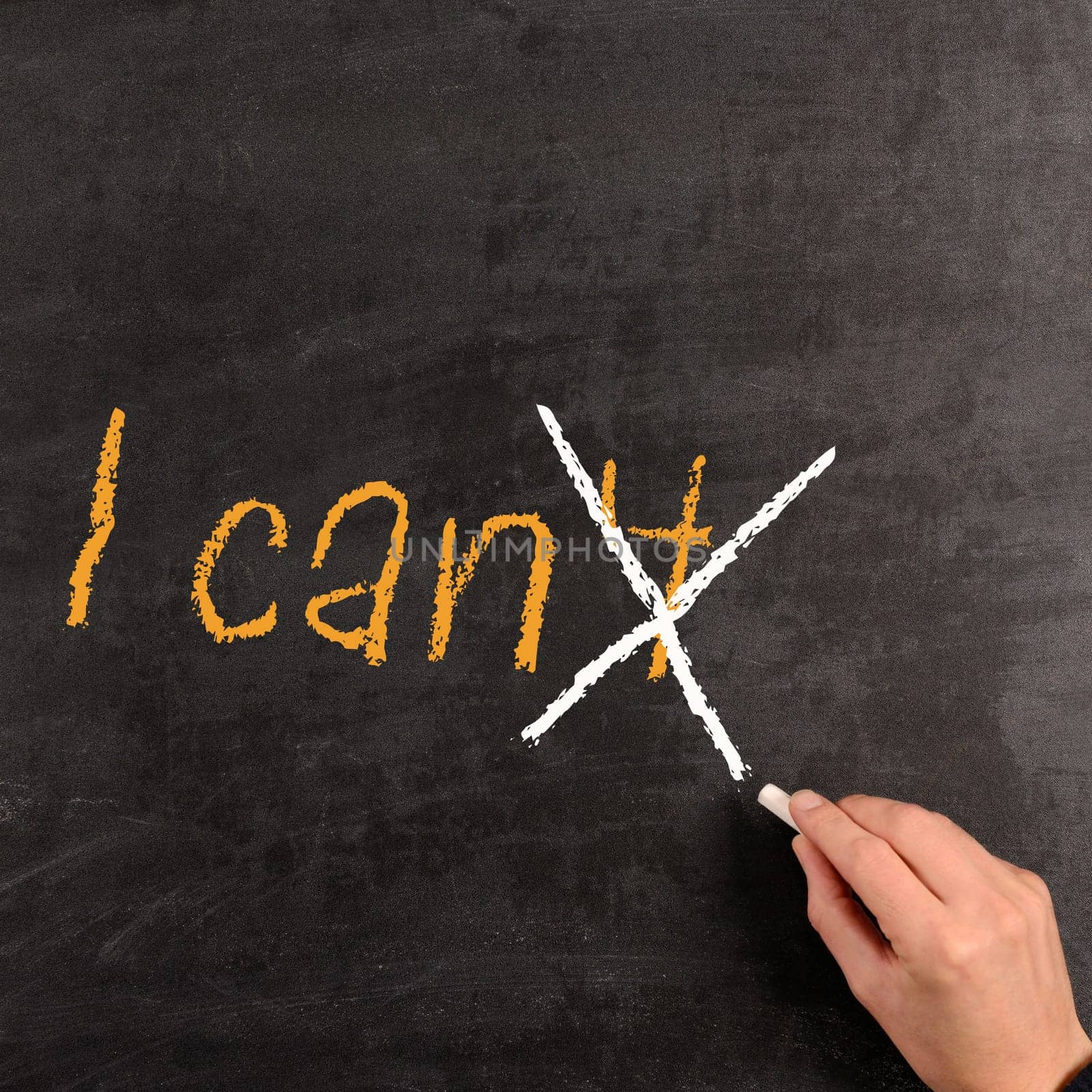 Hand writing with chalk on a blackboard the words "I can"""