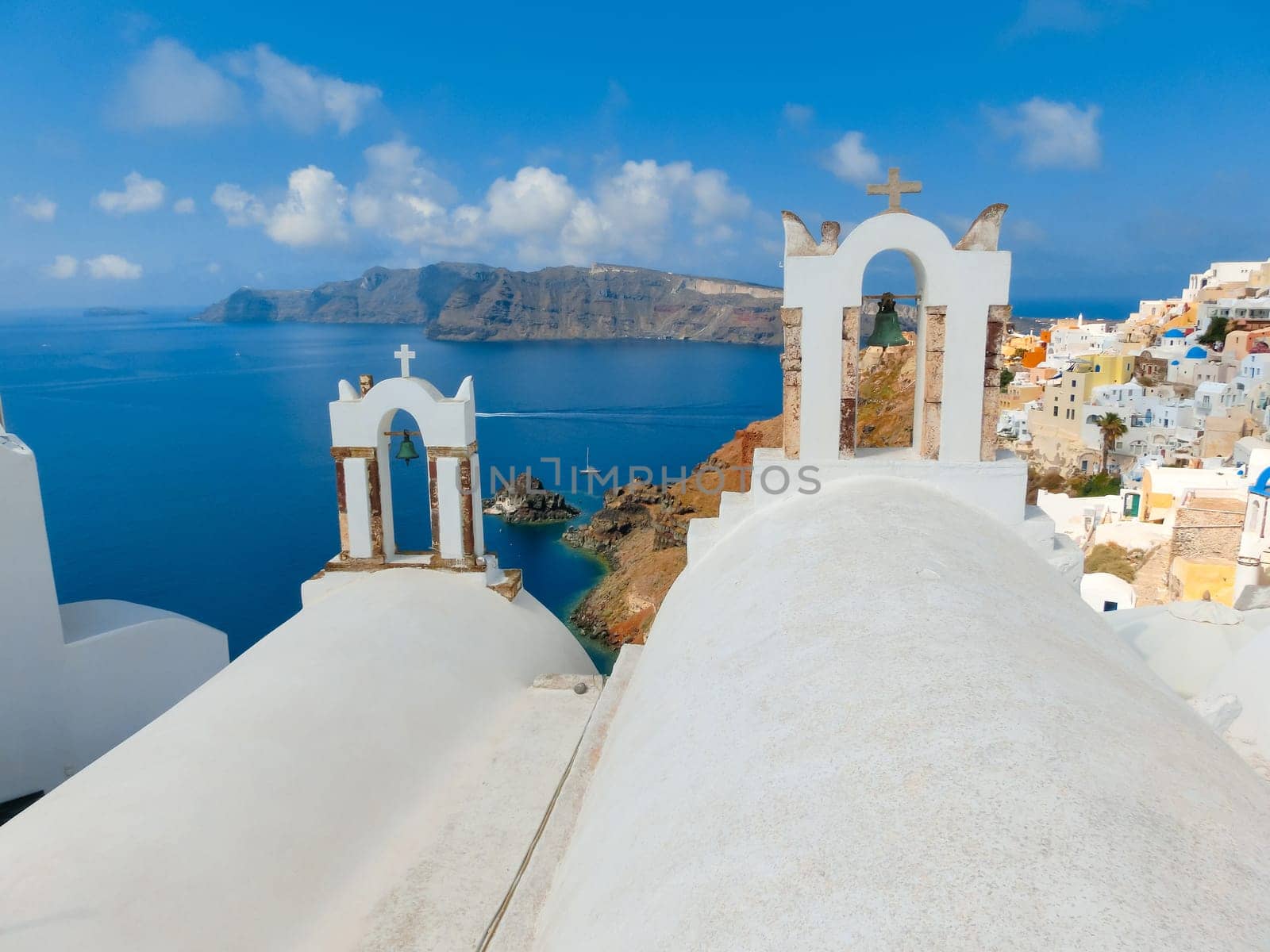 Oia, Greece - June 10, 2015: Santorini - The beautiful white bell tower on the sea in the background. Beautiful sea view on Santorini island, Oia, Greece.