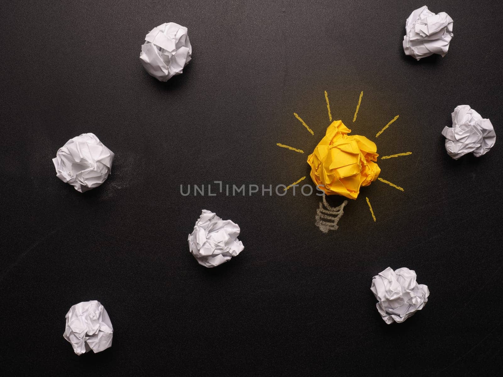 Crumpled paper on a chalkboard with a lightbulb