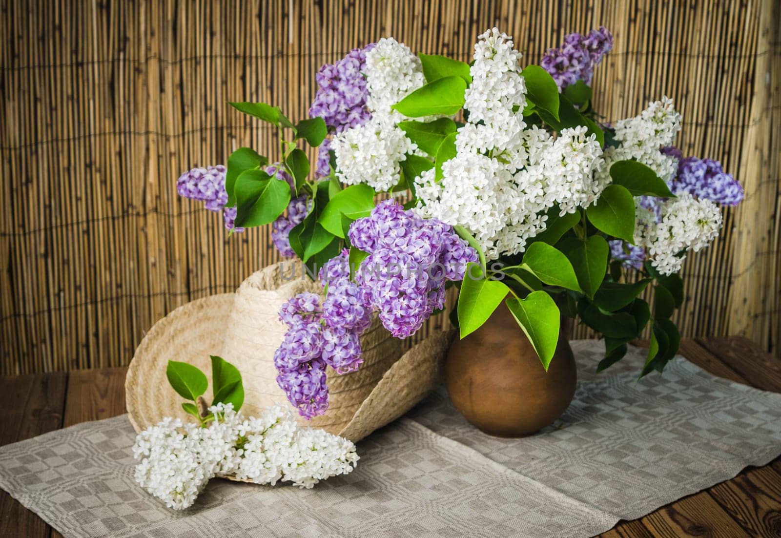 Still-life with a bouquet of lilacs and a straw hat, close-up