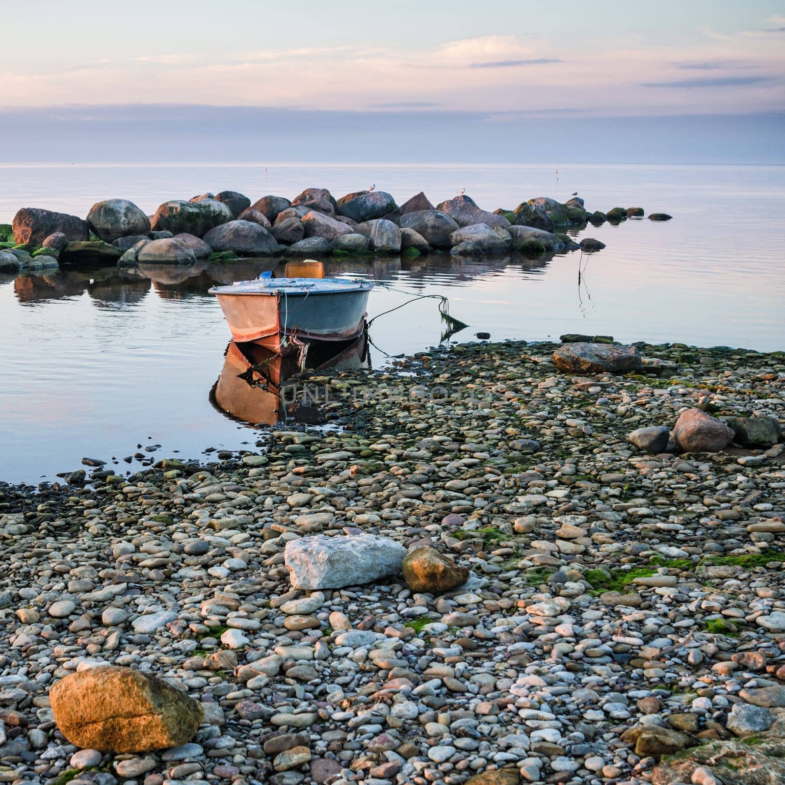 Rocky shore of the sea and fishing boat at sunset