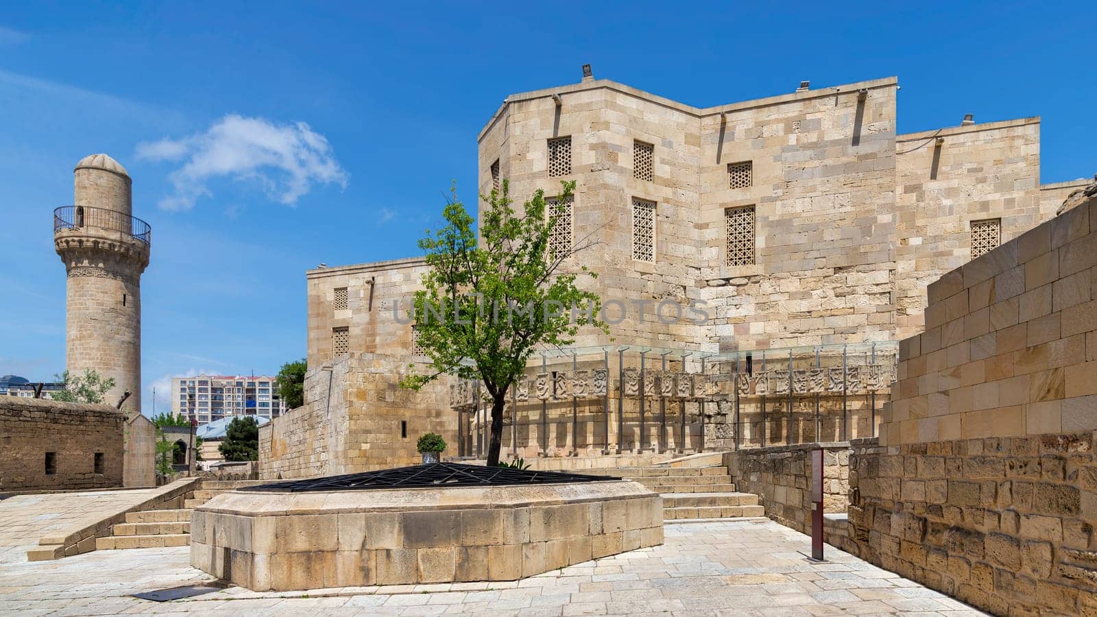 The historic Palace of the Shirvanshahs stands resplendently in the Old City of Baku, Azerbaijan, featuring intricate stonework that is illuminated by a vibrant blue sky