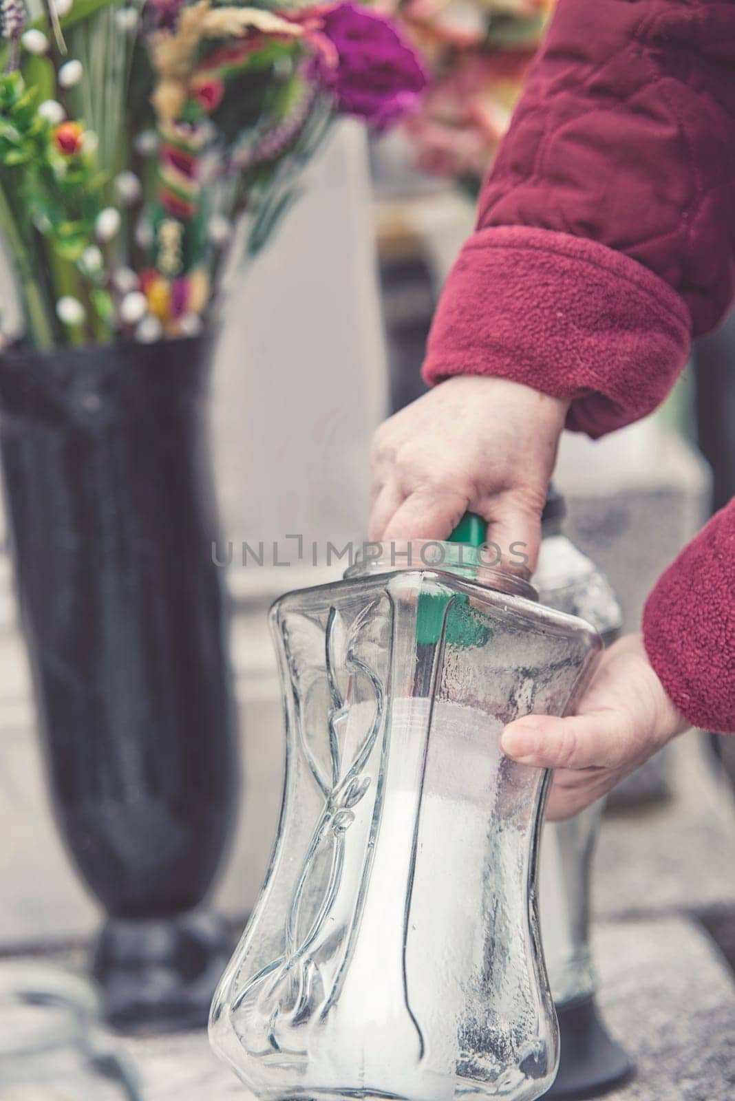 old woman at cemetery is lighting a candle