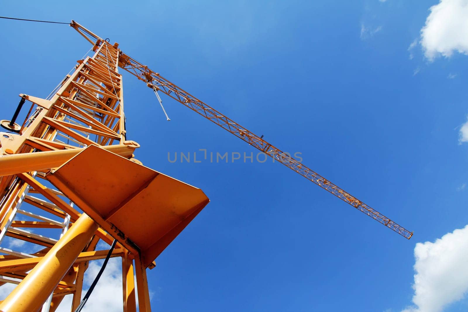 A yellow construction crane against the blue sky