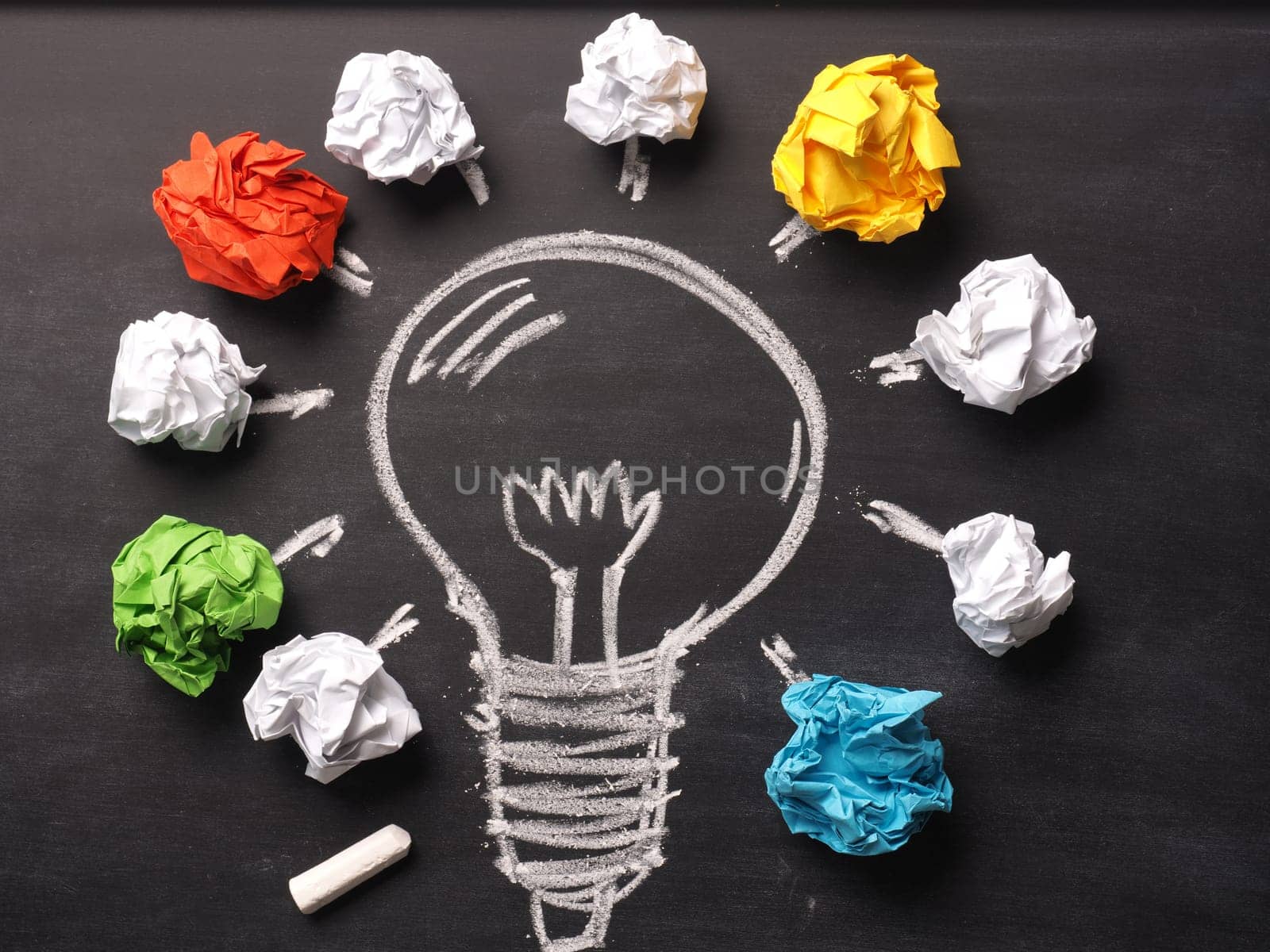 Crumpled paper on a blackboard with a handdrawn lightbulb, new idea concept background