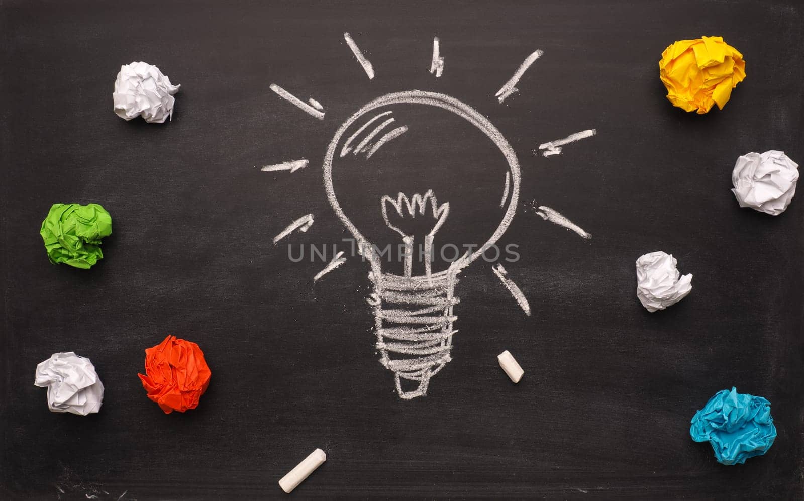 Crumpled paper on a blackboard with a handdrawn lightbulb, new idea concept background