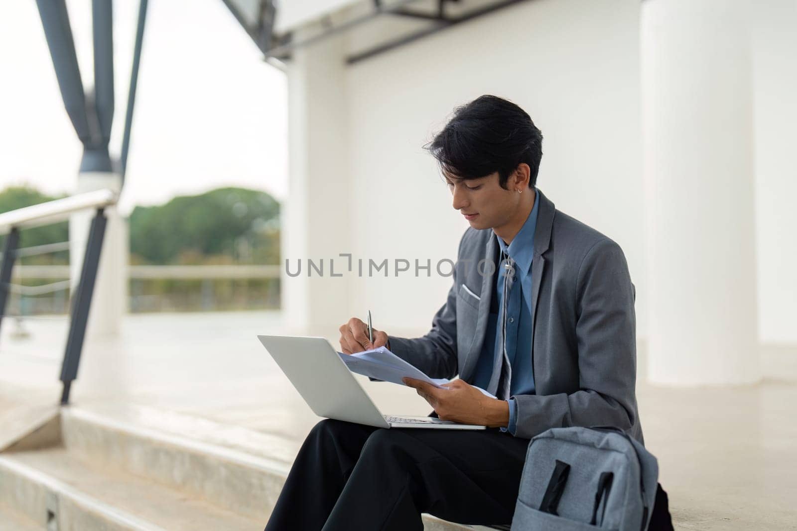 A young businessman notes insights from a financial report, combining outdoor relaxation with professional diligence.