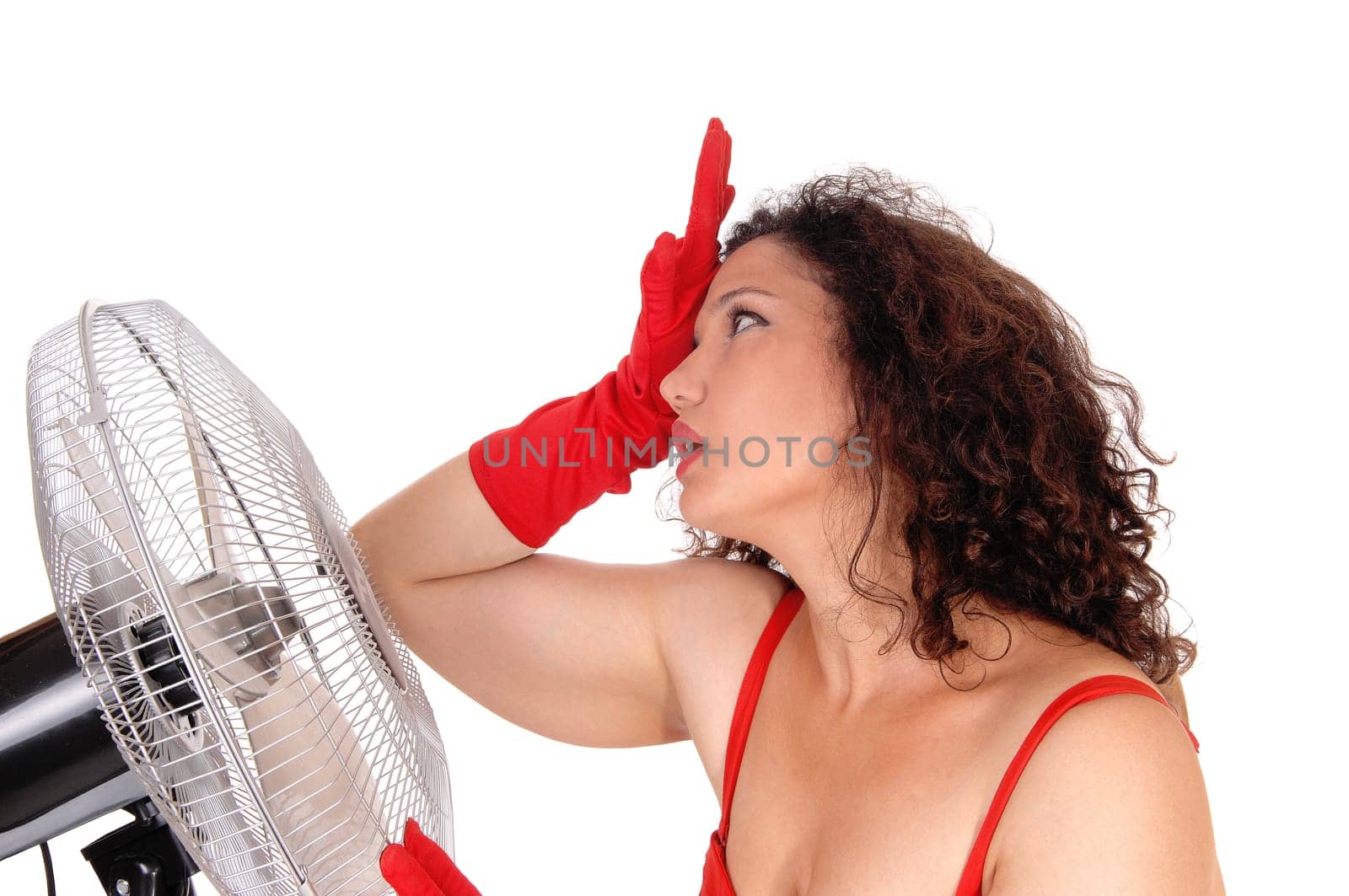 A young woman standing very hot in the heat in front so a big fan to.get some help from the heat, isolated for white background..