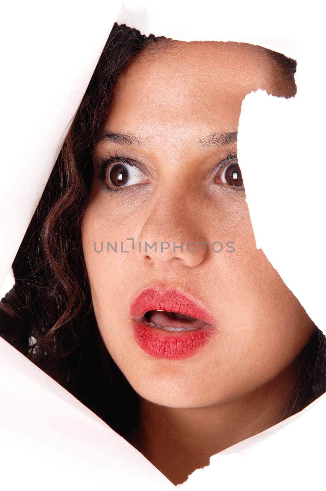 .A lovely woman looking through a hole in a paper, is shocked what she .see's, isolated for white background..