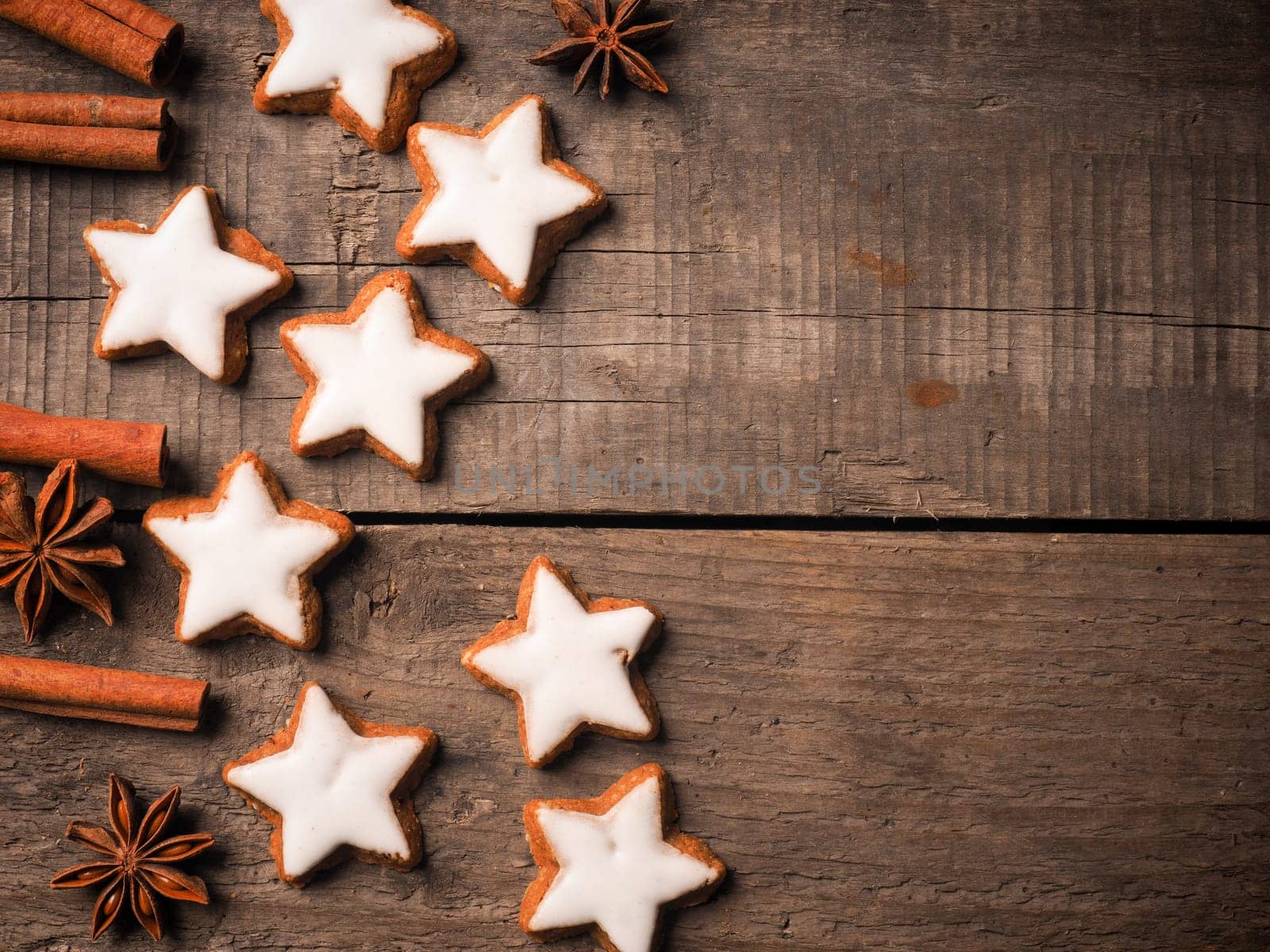 Christmas background with sweet cinnamon stars on a wooden table, space for text on the right