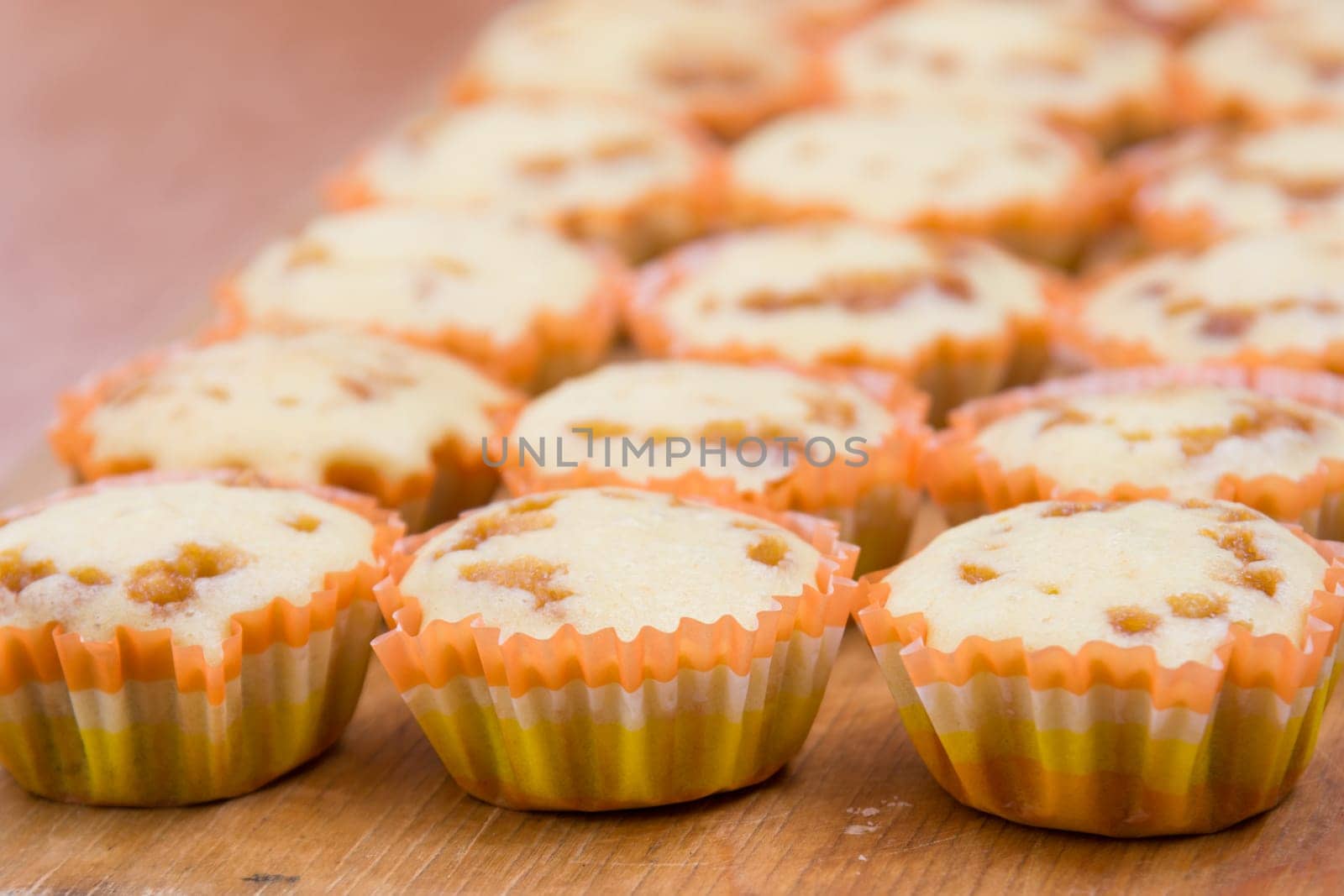 Three rows of freshly baked cupcakes in tins