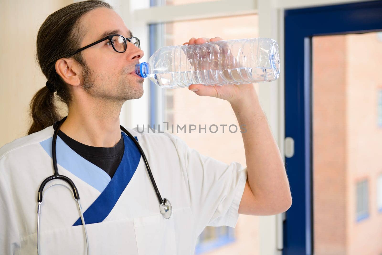 long haired male nurse is thirsty and drinking water