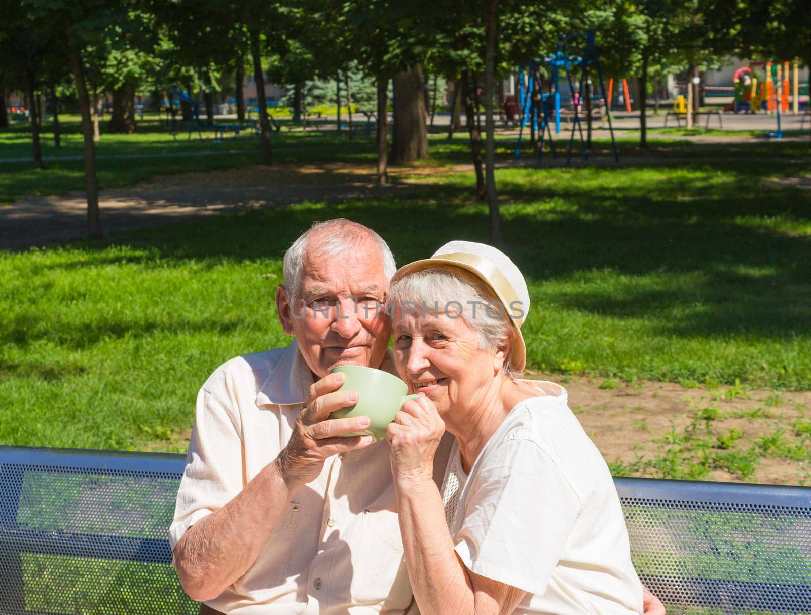 The happy old couple drinking tea in the summer on a walk in park