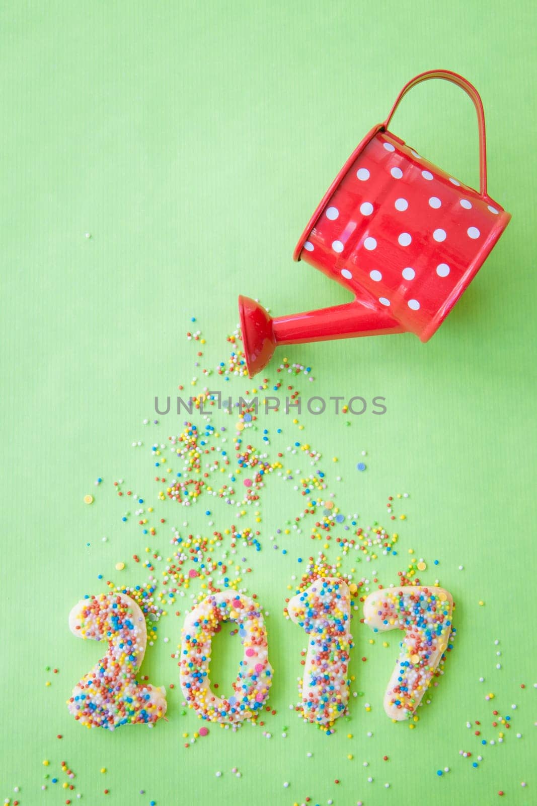 Biscuits with colorful sprinkles for New Year 2017 on a green background