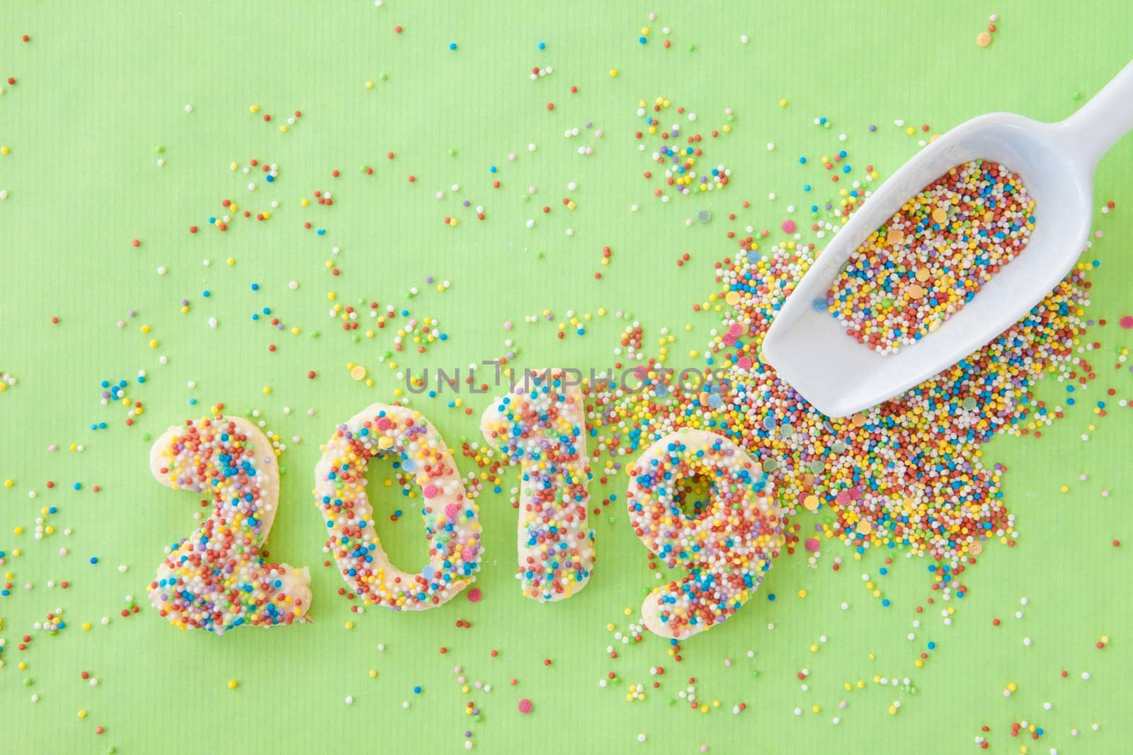 Cookies with colorful sprinkles for the New Year 2019 on a green background