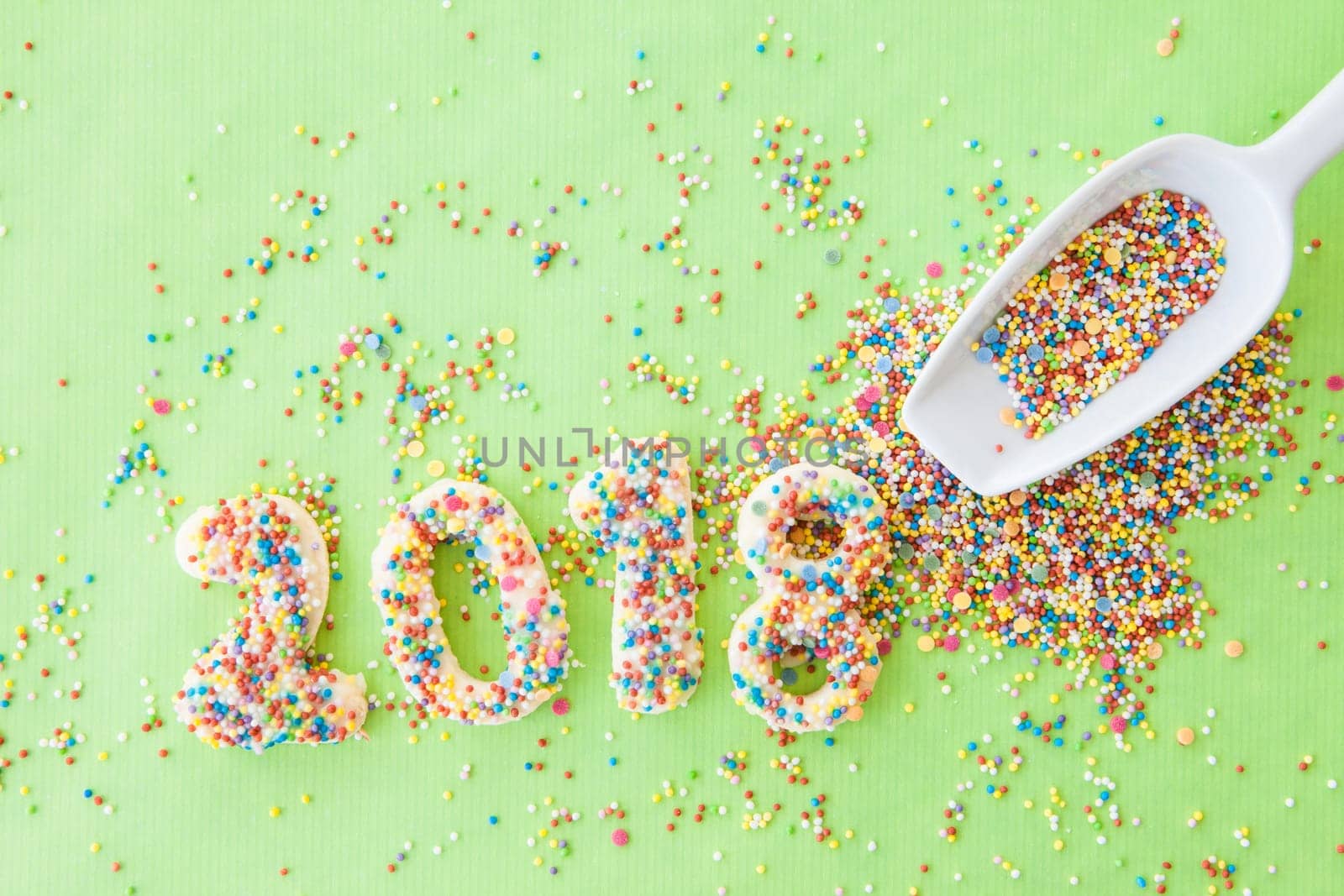 Cookies with colorful sprinkles for the New Year 2018 on a green background