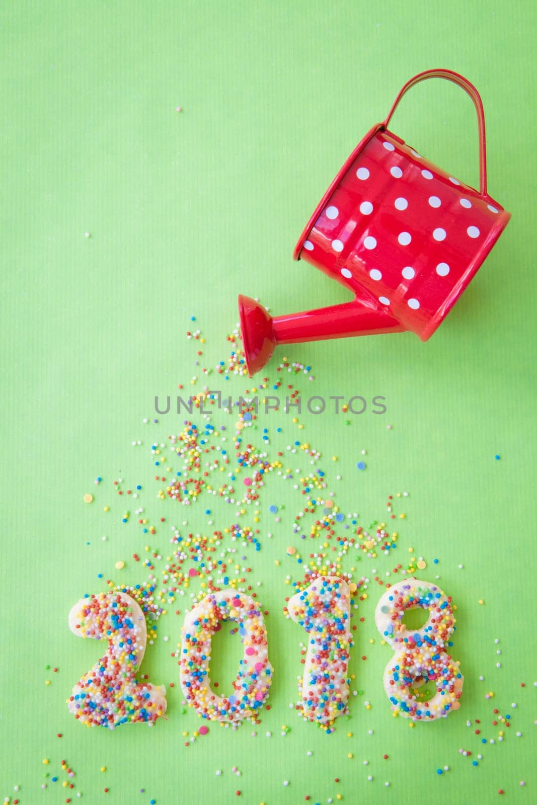 Cookies with colorful sprinkles for the New Year 2018 on a green background