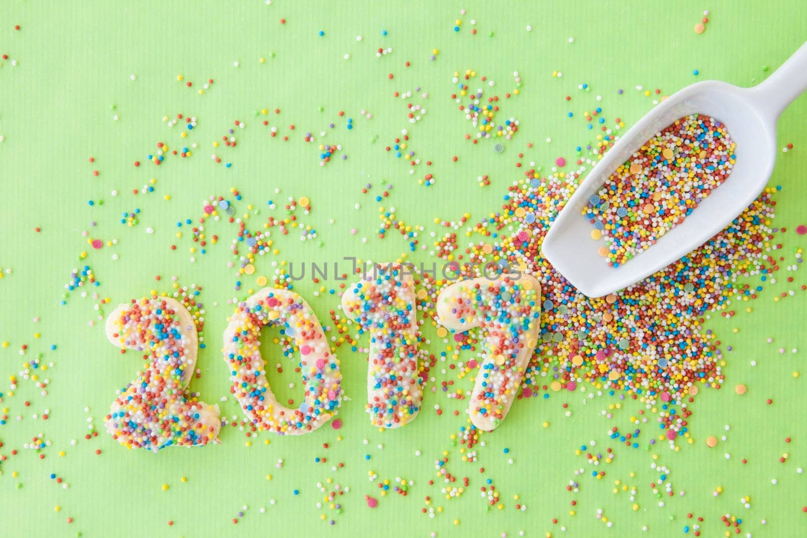 Cookies with colorful sprinkles for the New Year 2017 on a green background