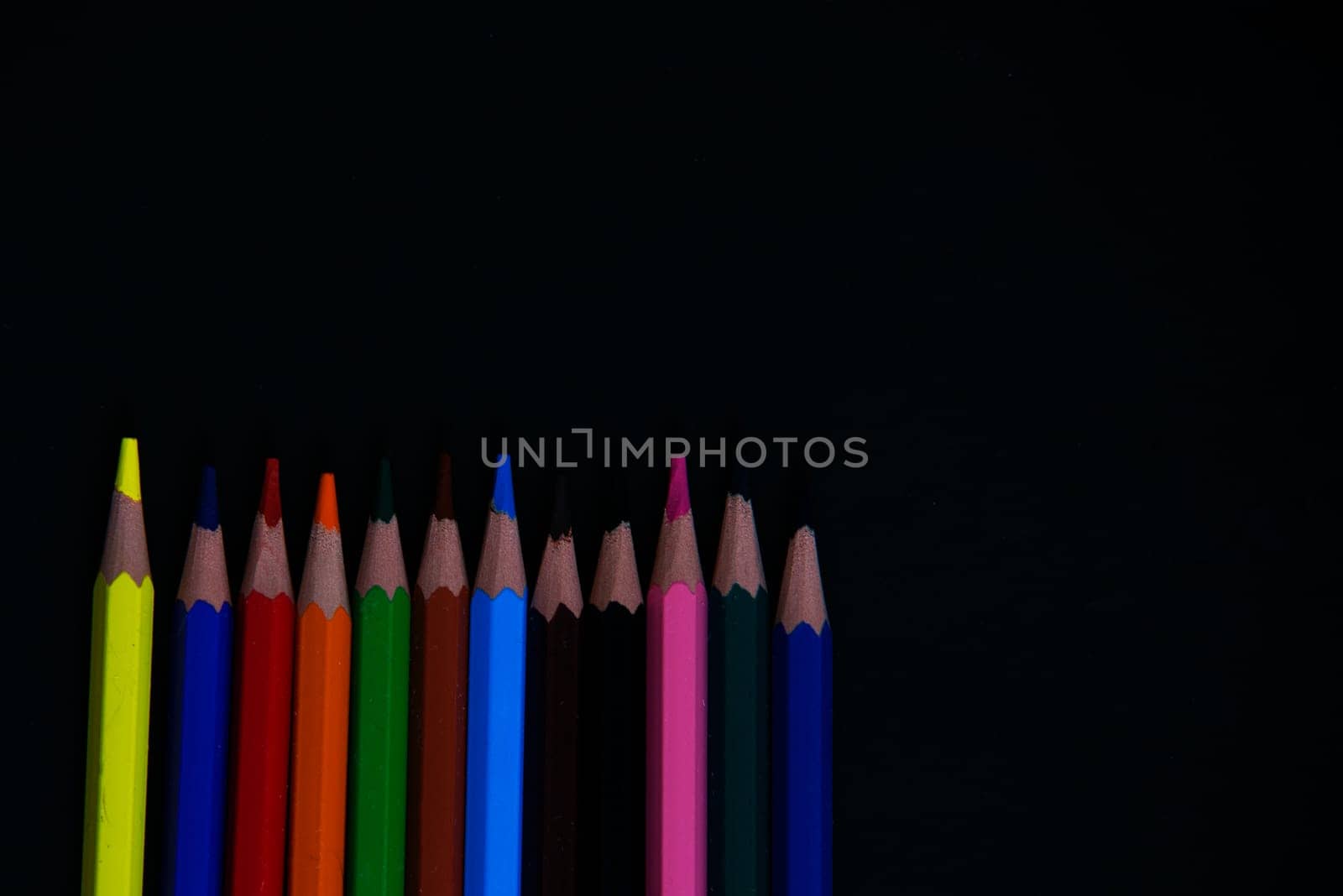 colorful pencils isolated on a black background paper