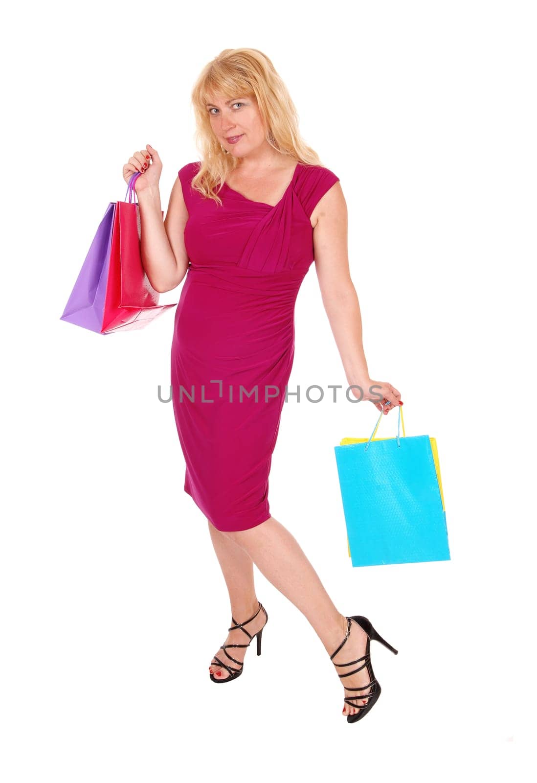 A pretty woman in her forties holding up the shopping bag's, standing.in high heels isolated for white background..