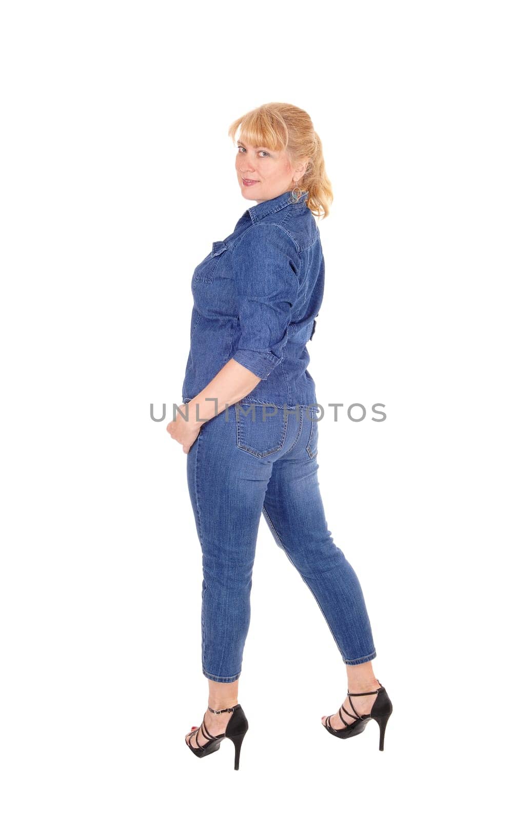 A pretty woman in jeans pants and jacket standing from the back, looking.over her shoulder, isolated for white background..