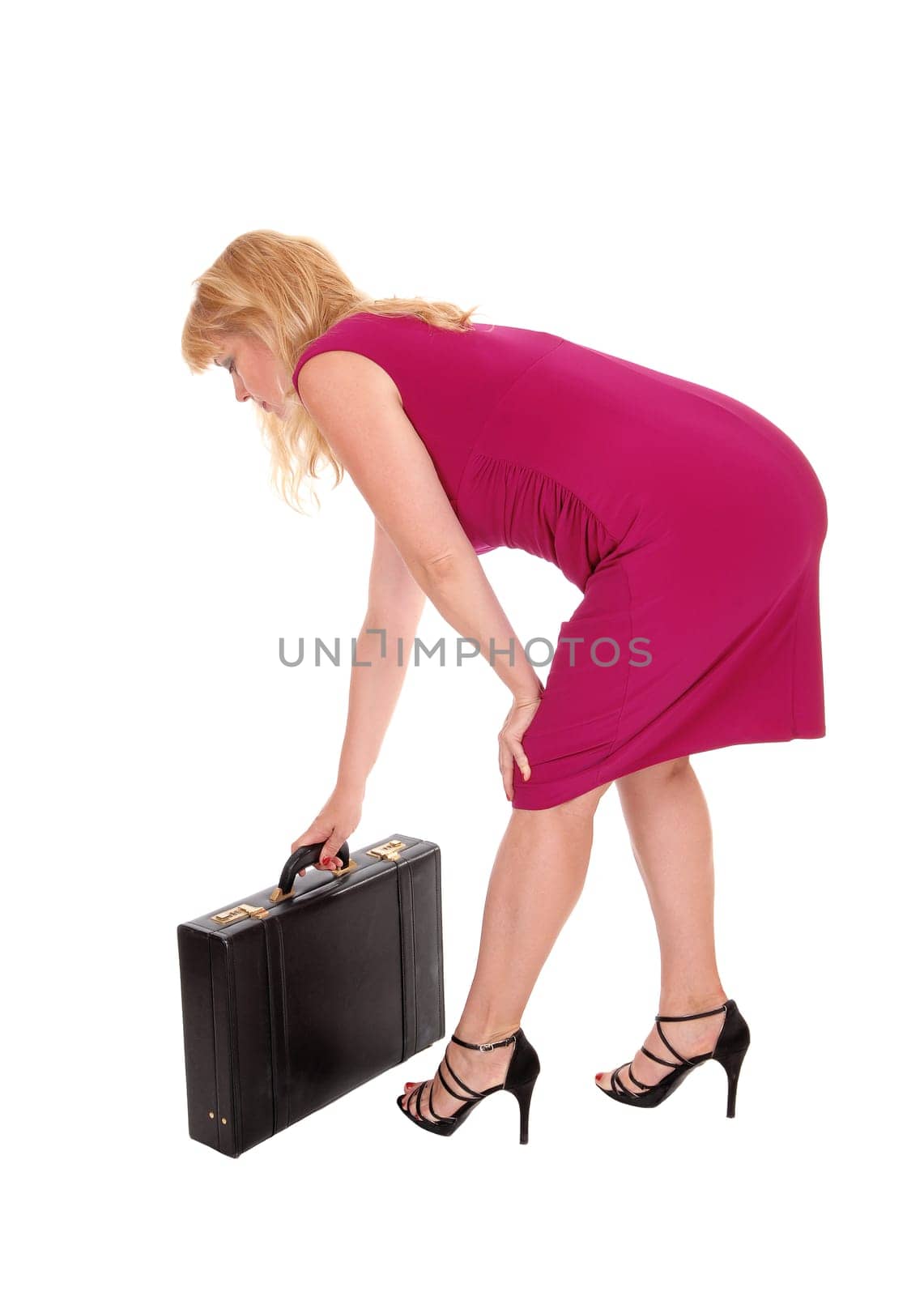A business woman in a red dress bending down picking up her brief-.case, isolated for white background..