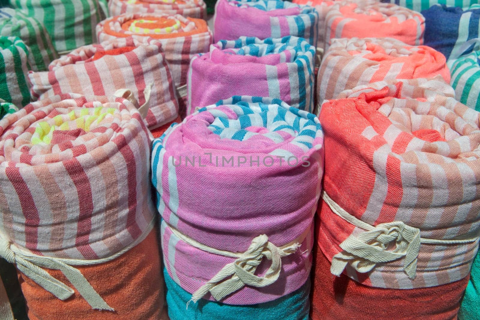 Loads of many rolled colorful light cotton blankets. Closeup