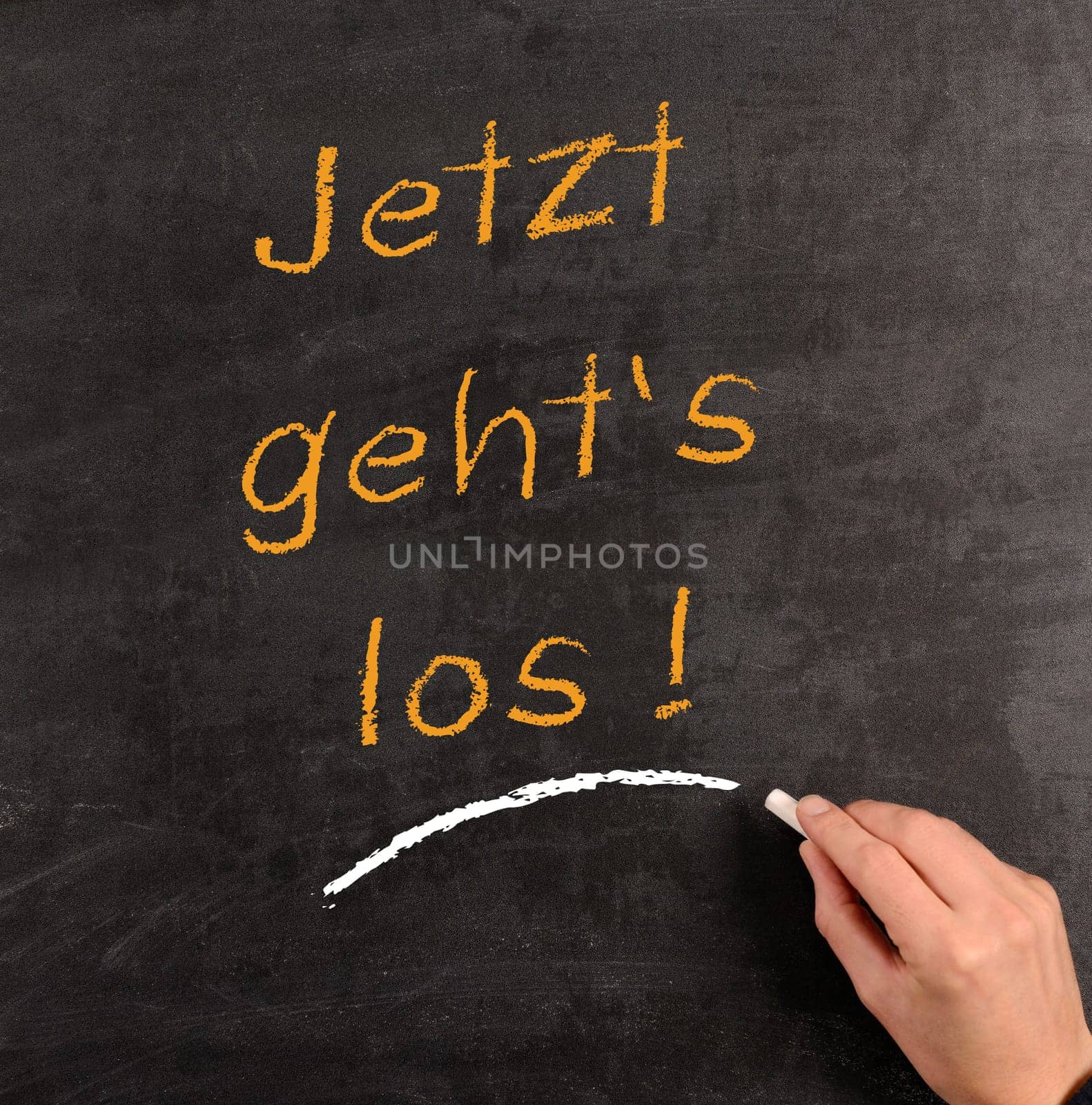 Hand writing with chalk on a blackboard the German words "Start now!"""