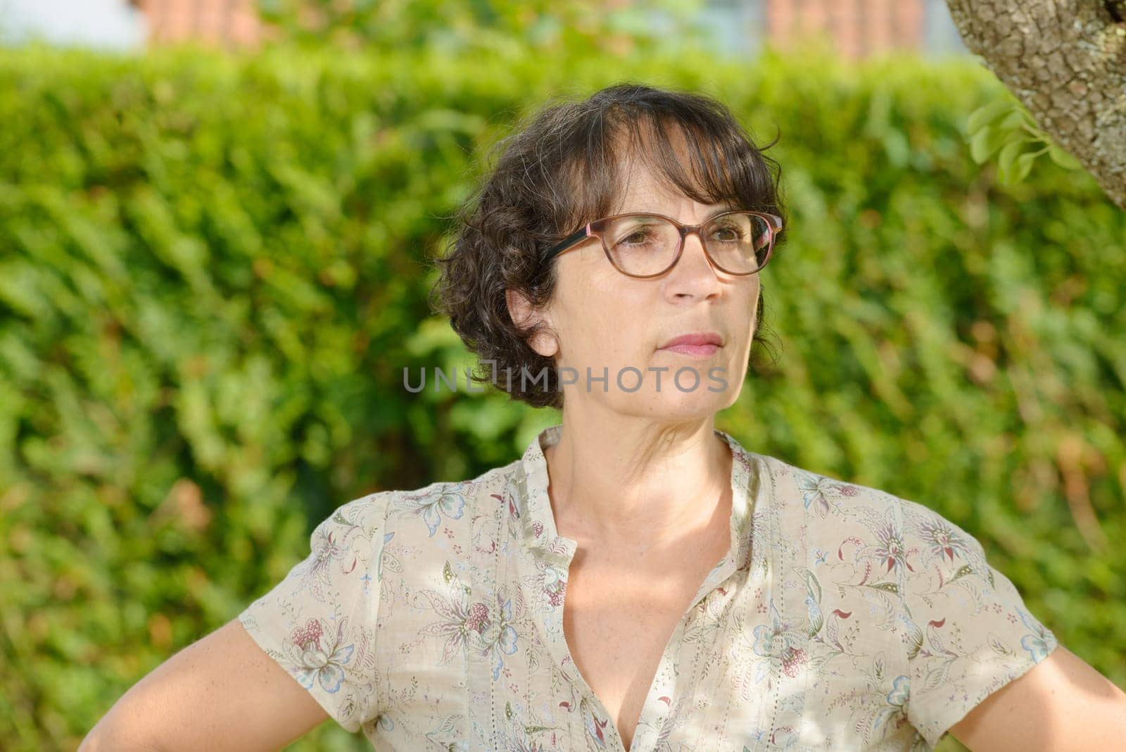 a portrait of a mature woman with glasses in his garden