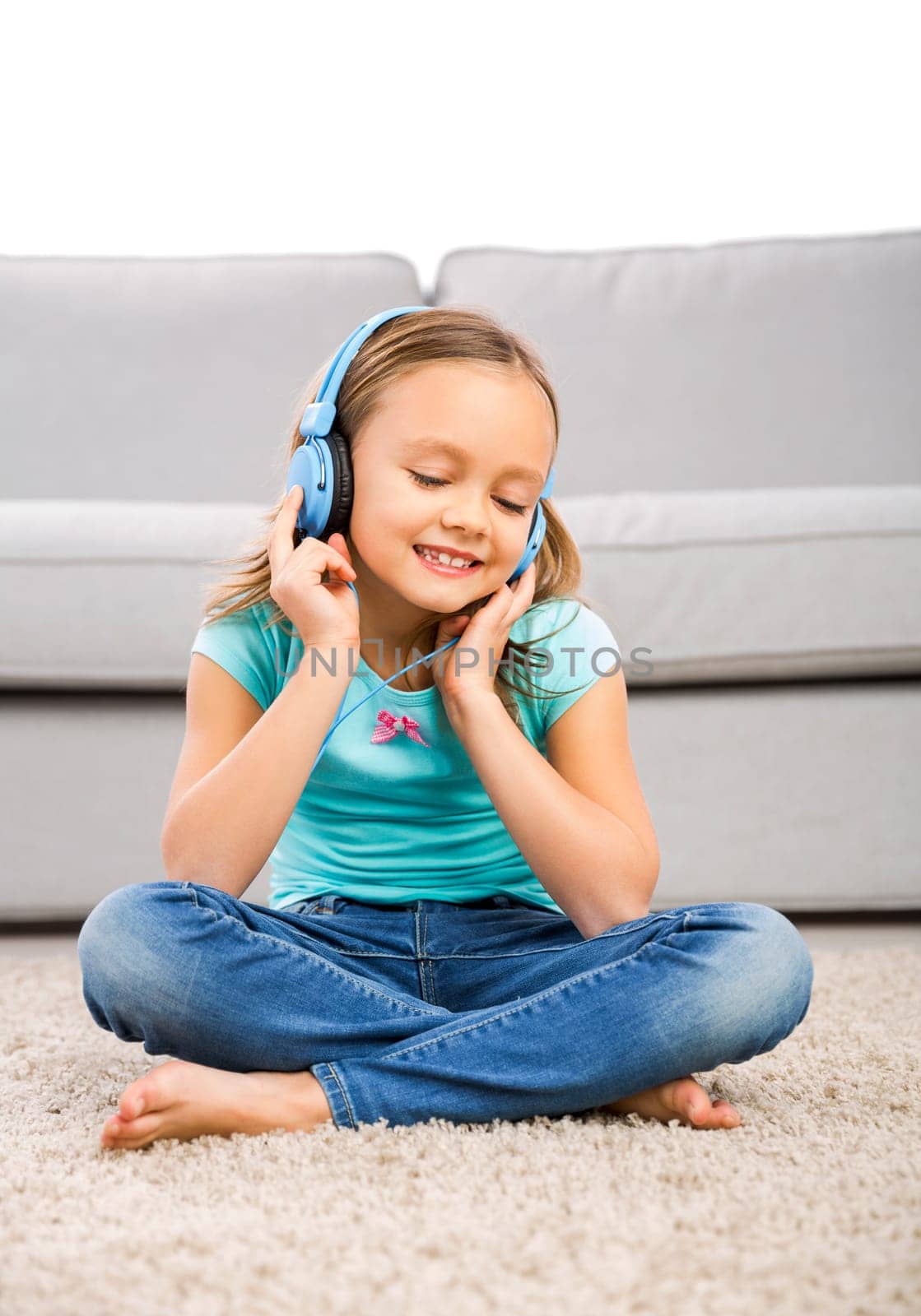 Little blonde girl at home listen music with headphones