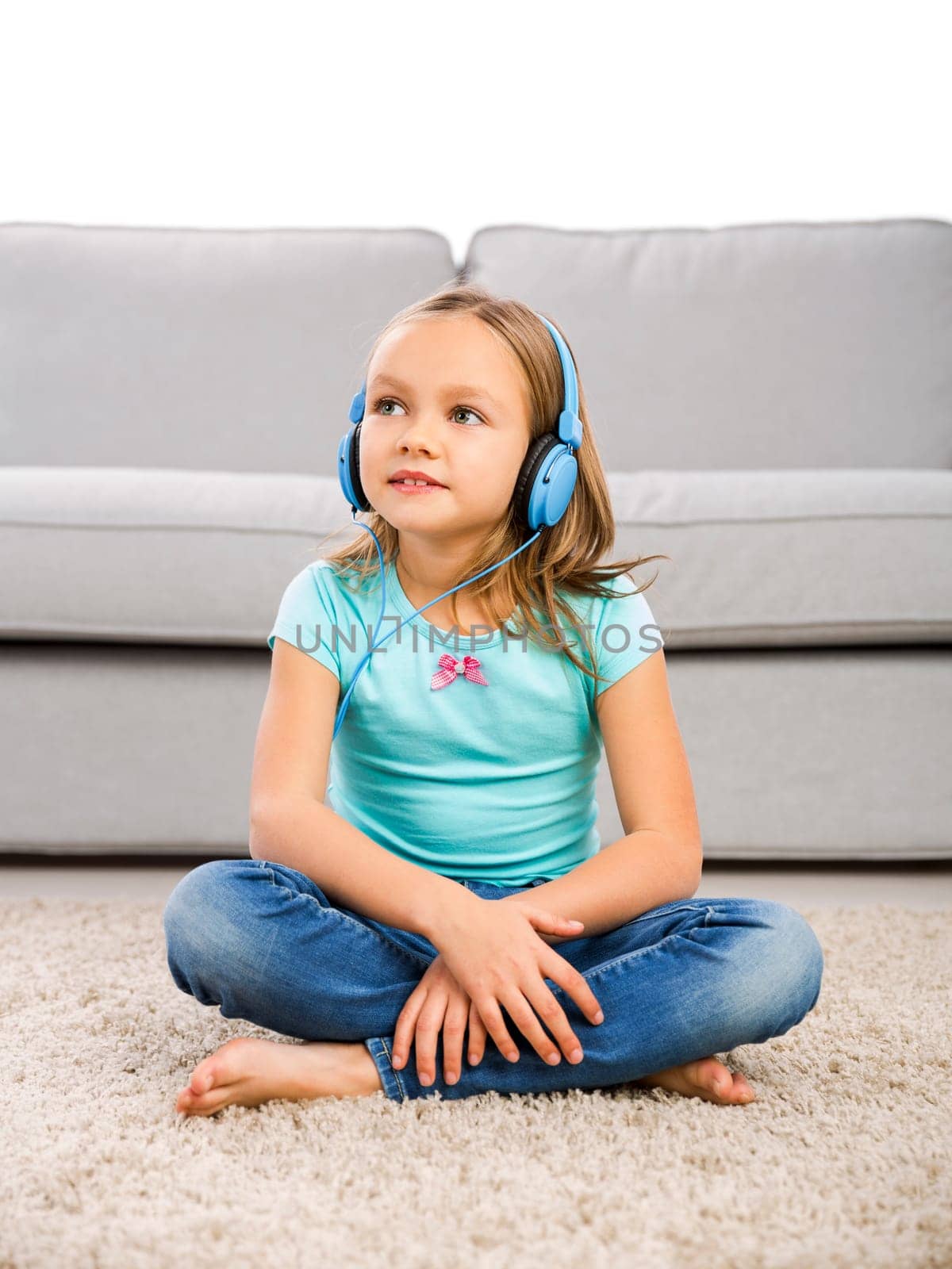 Little blonde girl at home listen music with headphones