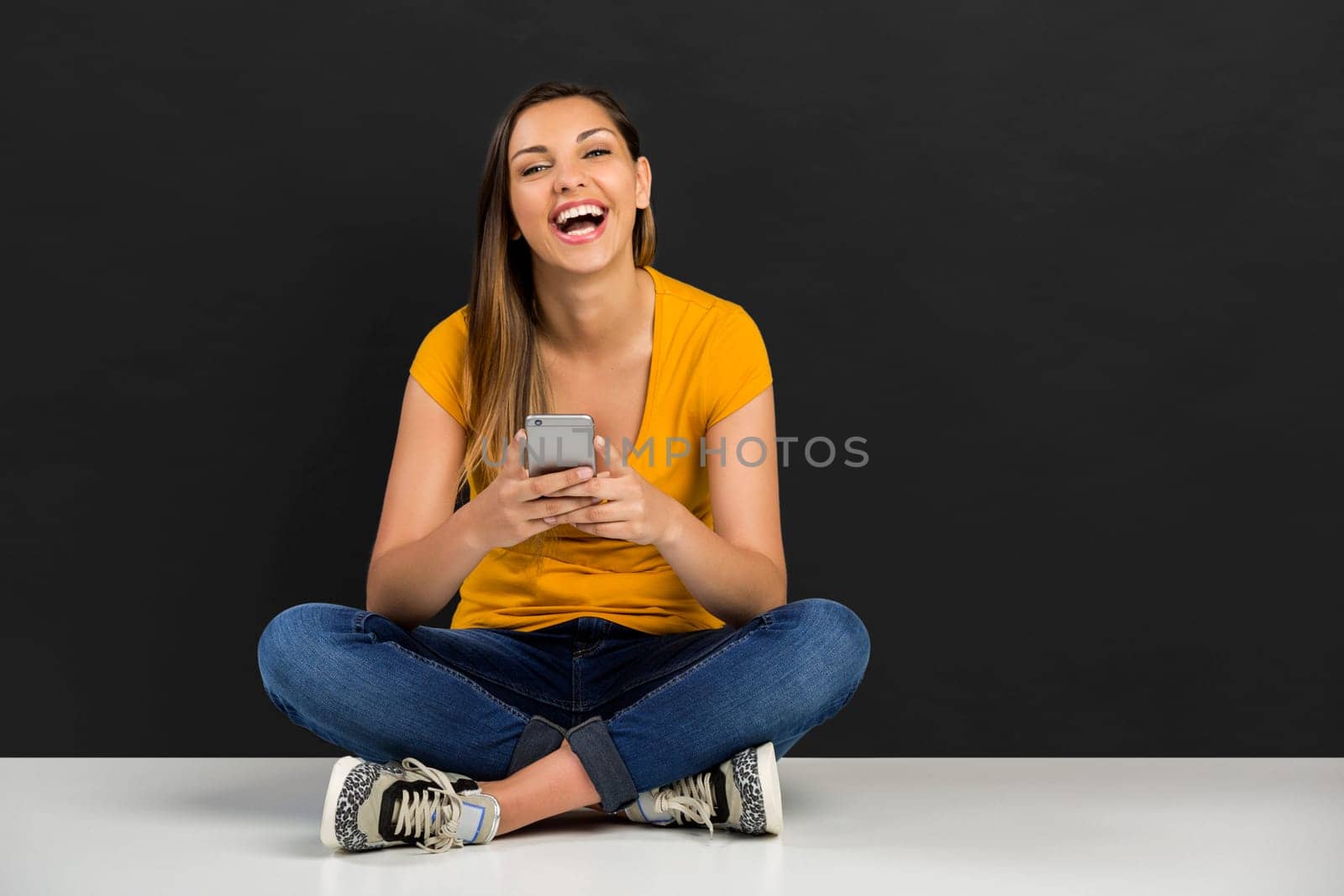 Beautiful woman lying in the floor and texting a sms