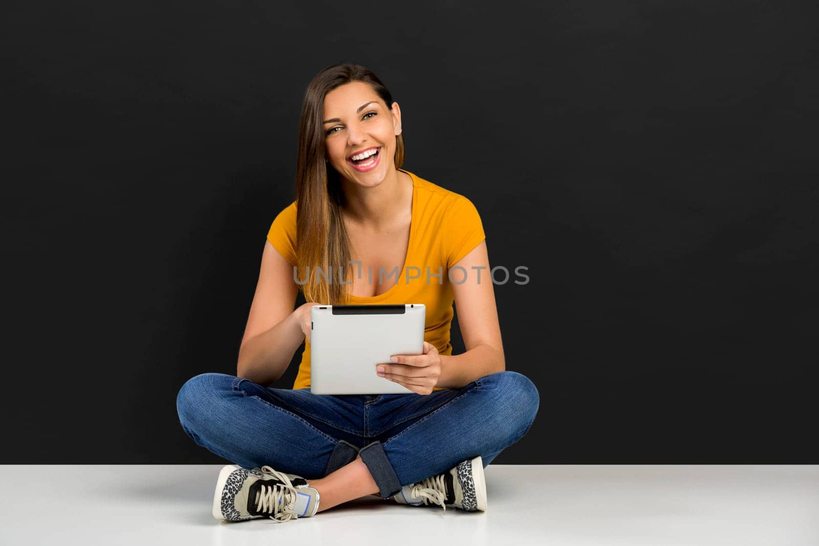 Beautiful woman sitting on the floor working with a tablet