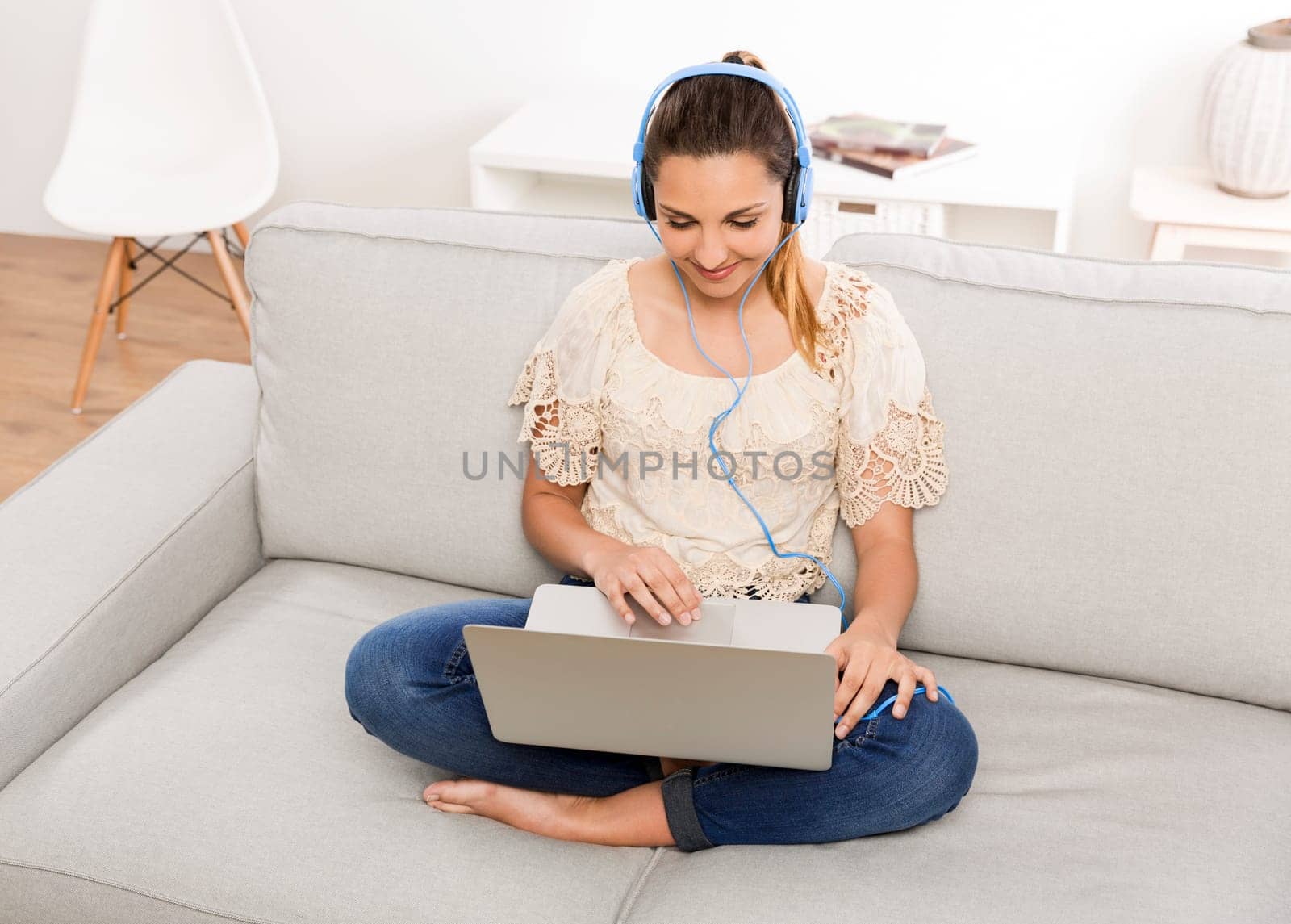 Beautiful woman at home working on her laptop and listening music